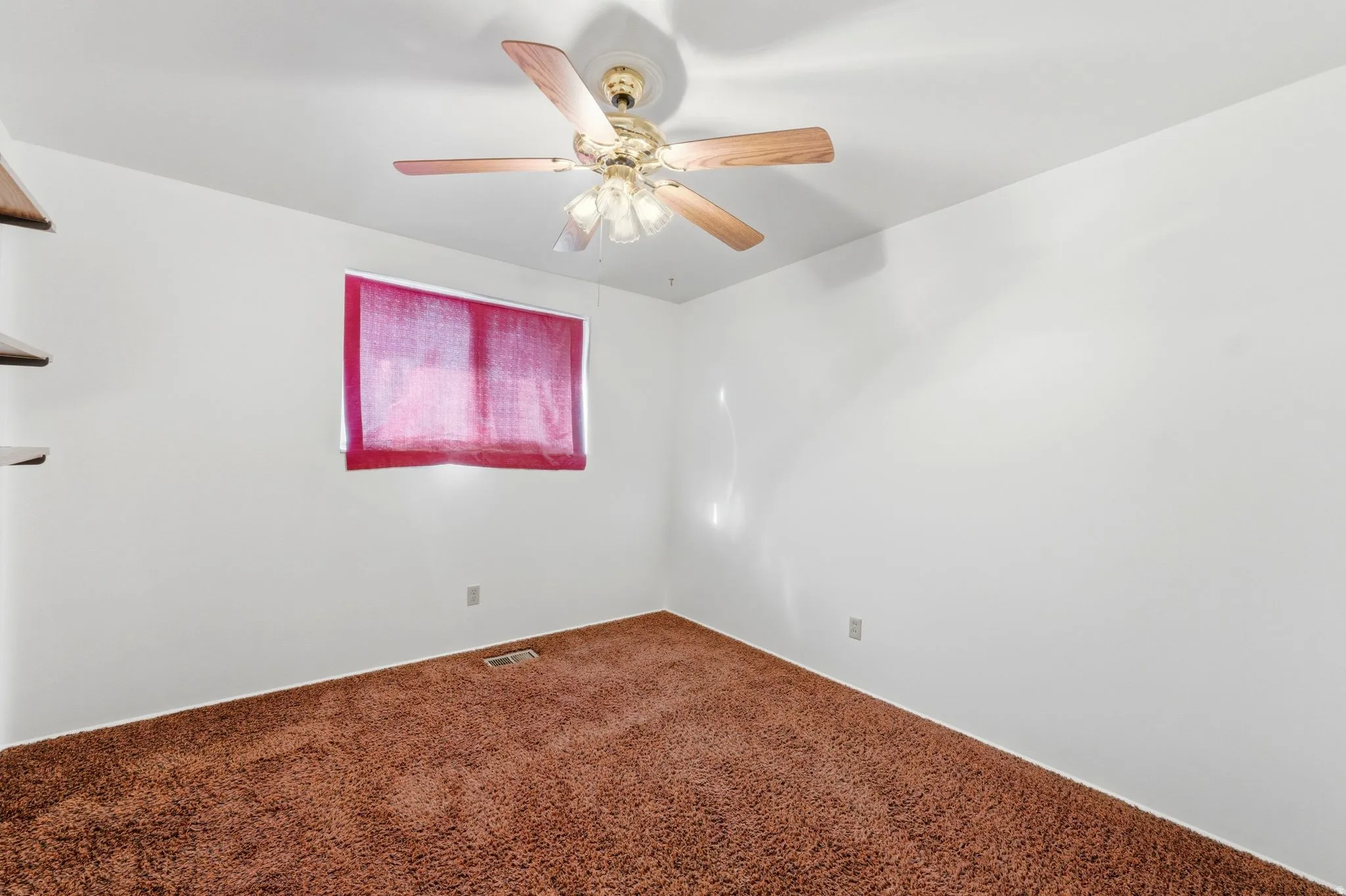Spare room featuring carpet and ceiling fan