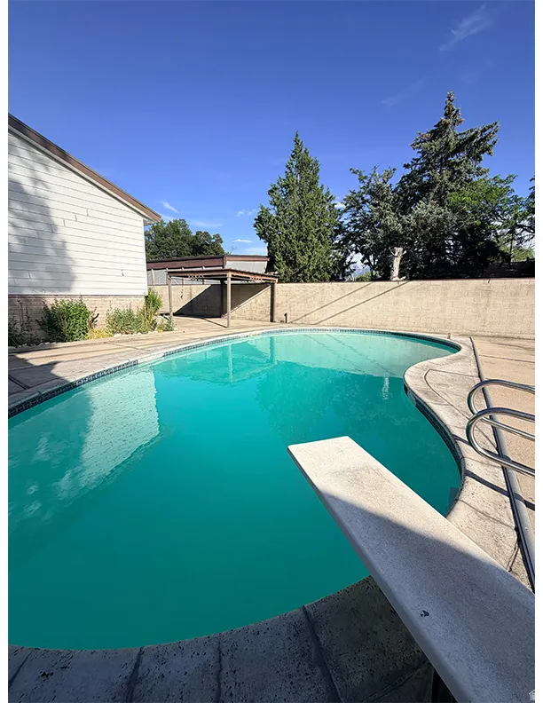 In-ground swimming pool with a diving board, surrounded by concrete decking
