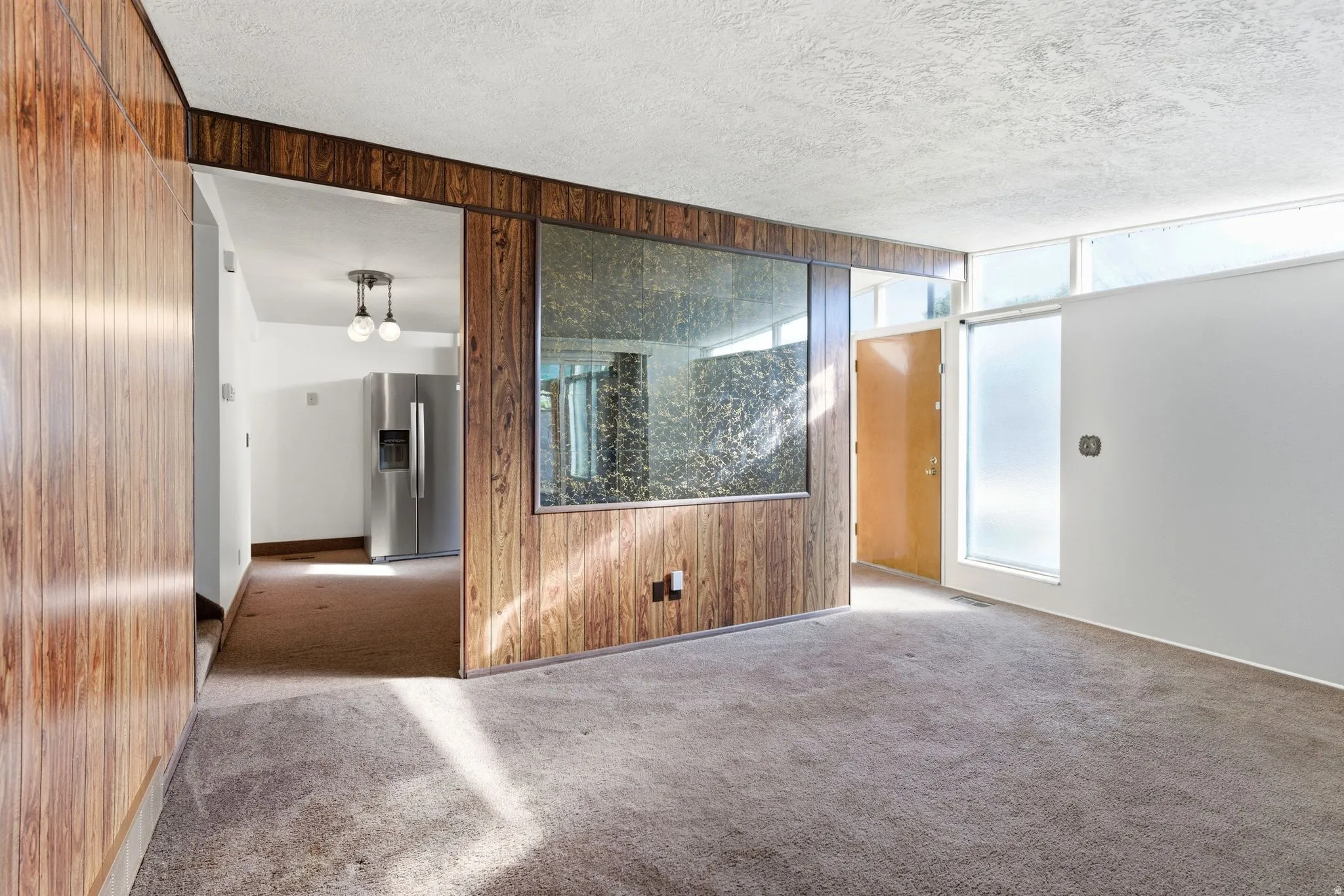 Carpeted empty room featuring wood walls and a textured ceiling