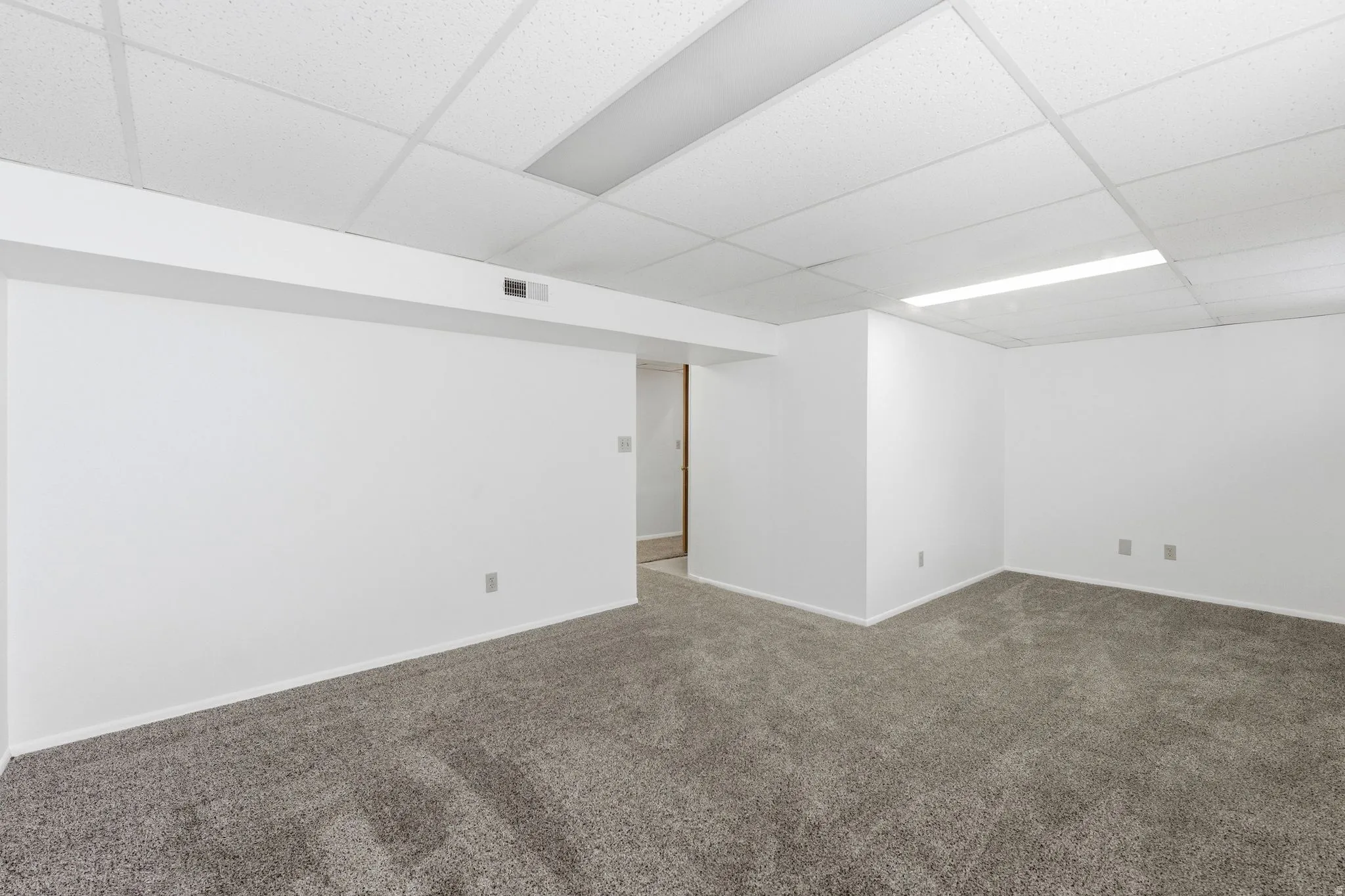 Unfurnished room featuring a drop ceiling and dark carpet
