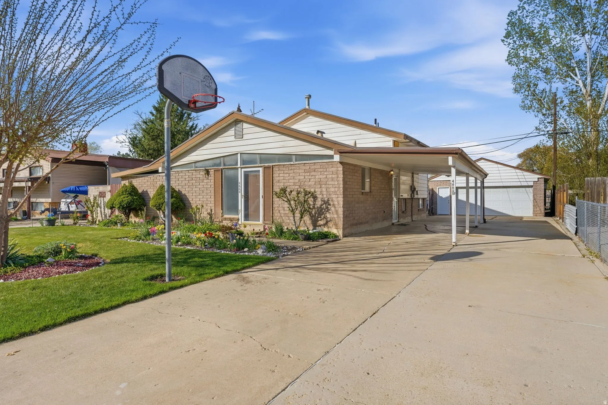 Back of property with an outbuilding, an attached carport, brick siding, and concrete driveway