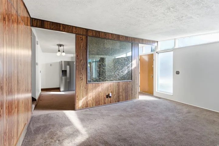 Carpeted empty room featuring wood walls and a textured ceiling