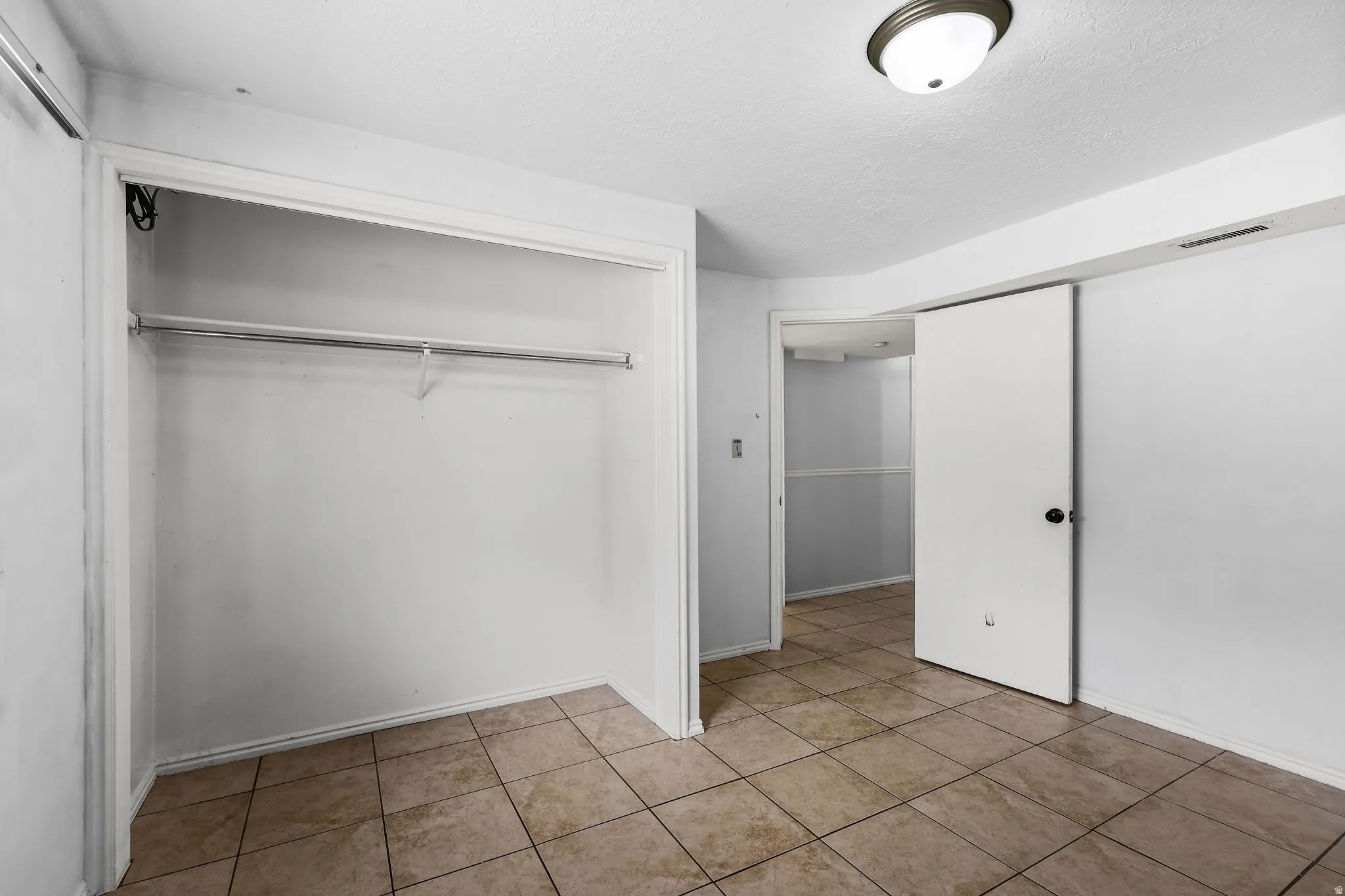 Room featuring neutral-toned tile flooring, white walls, and a flush-mount ceiling light