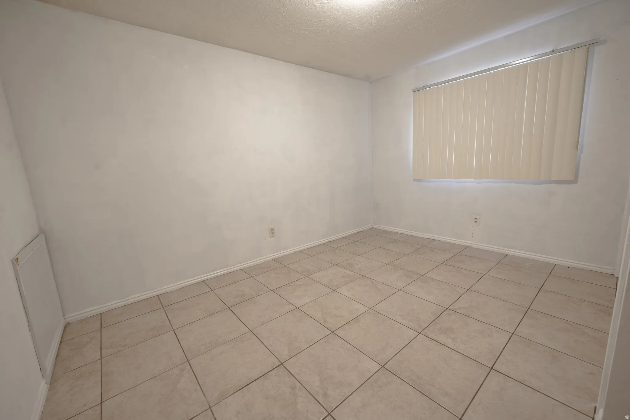 Unfurnished room featuring a textured ceiling and light tile patterned floors