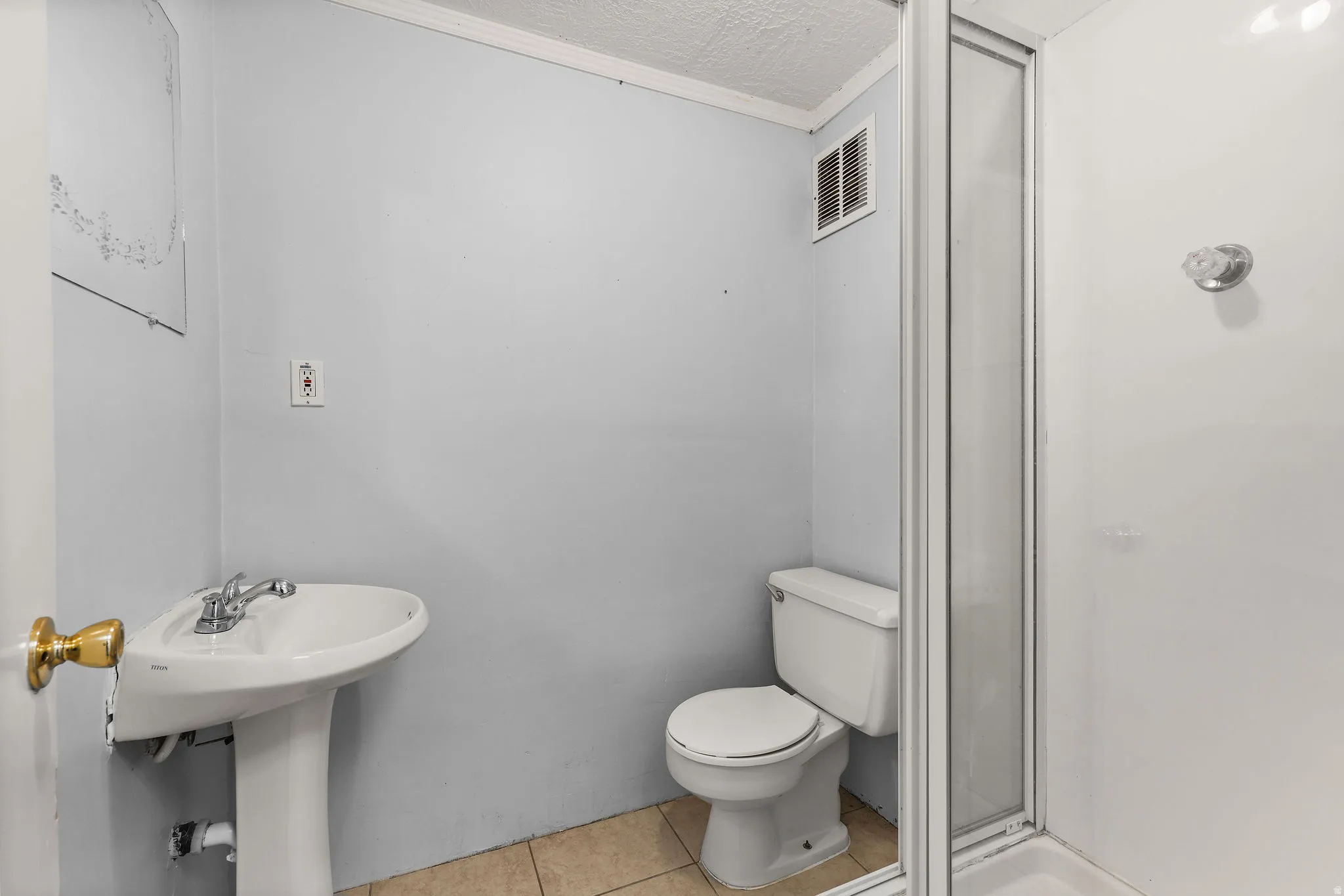 Full bathroom featuring a pedestal sink, commode, and a shower stall with a framed glass enclosure
