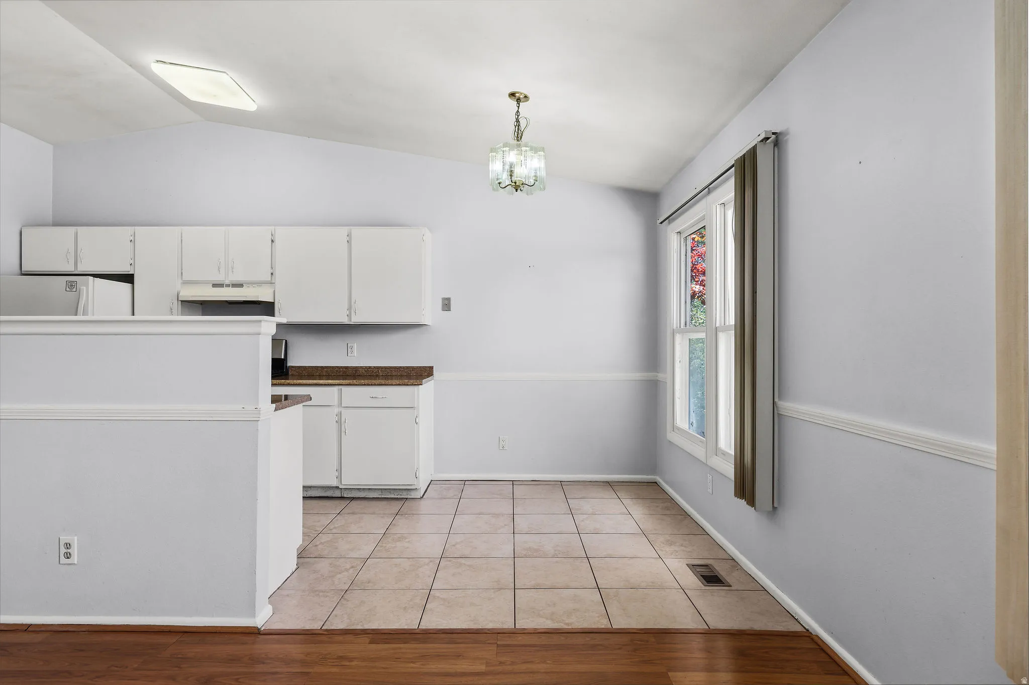 Open-concept kitchen and dining area featuring white cabinetry, wood-finish countertops, and a tile floor