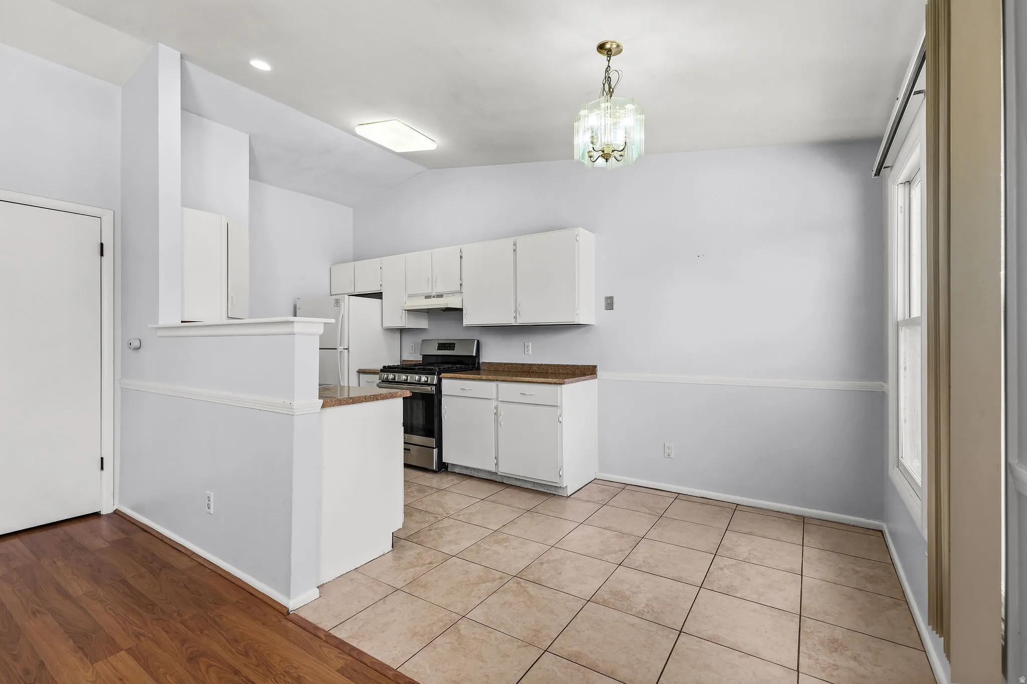 Kitchen and dining area featuring white cabinetry, stainless steel appliances, and a gas range