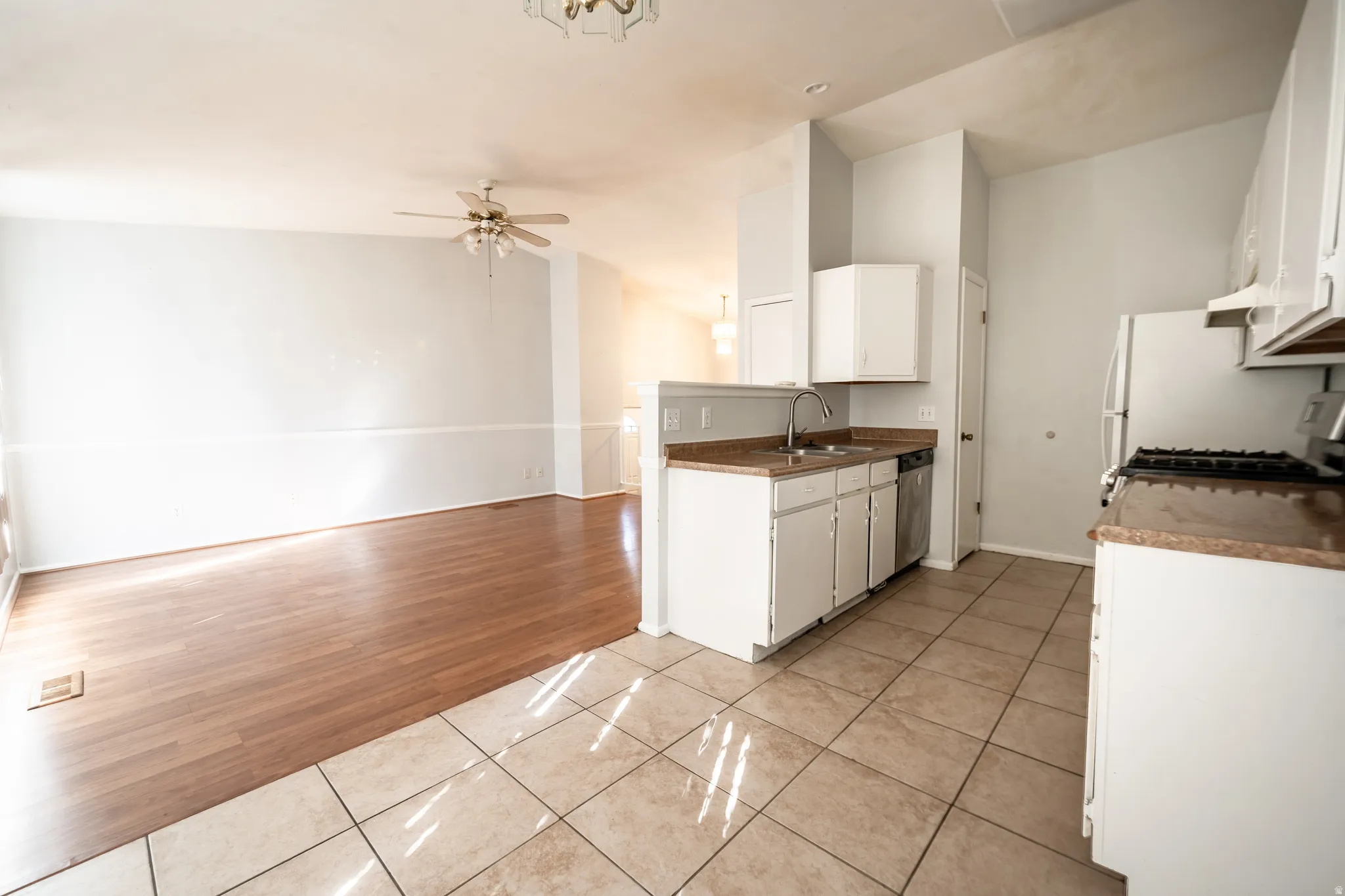 Kitchen with light tile patterned floors, white cabinetry, vaulted ceiling, gas stove, and open floor plan