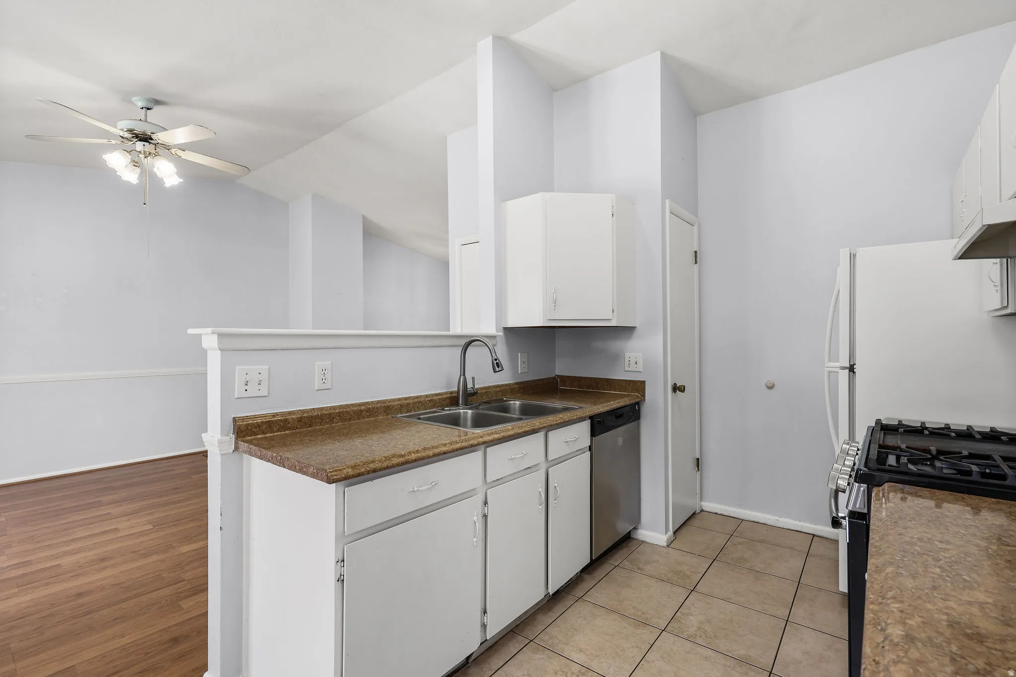 Kitchen featuring white cabinetry, a double basin sink, stainless steel dishwasher, and a gas range