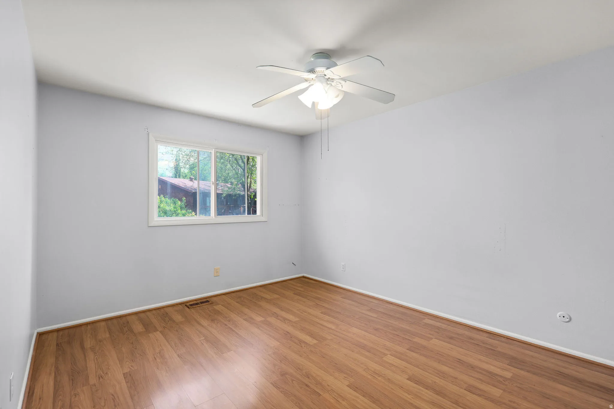 Interior room with wood-finish flooring, white baseboards, and light gray walls