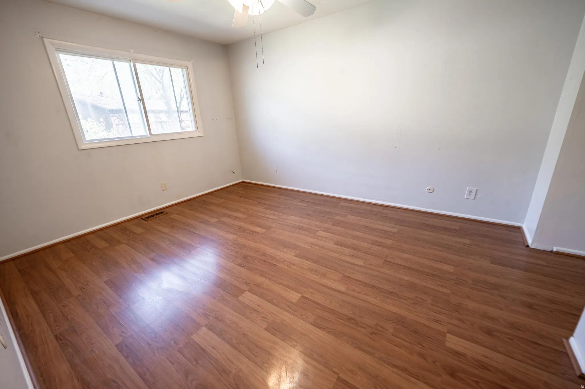 Spare room with wood finished floors and ceiling fan