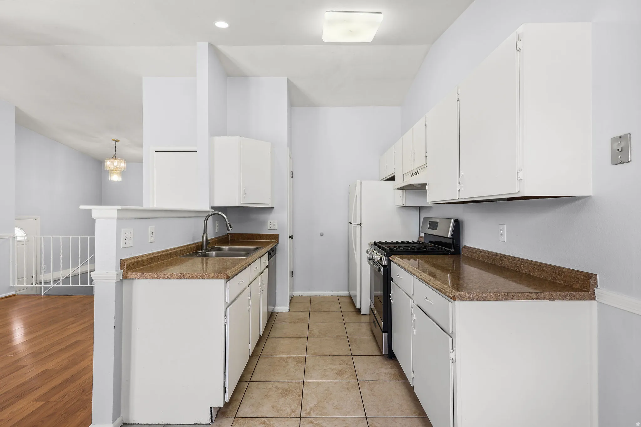 Galley kitchen featuring white cabinetry, light-toned countertops, and a dual basin sink