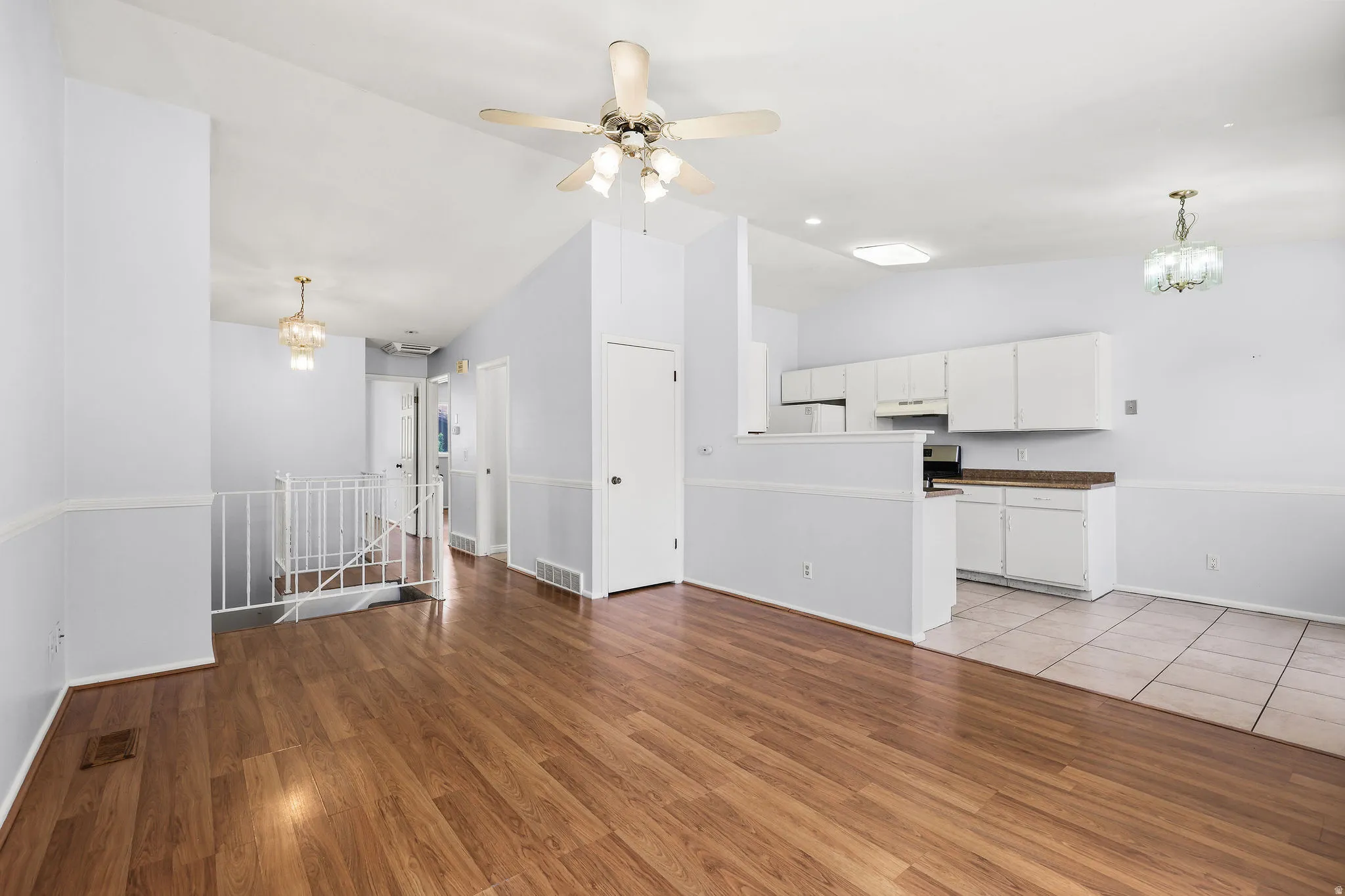 Open-concept living area featuring wood-finish flooring, a contemporary ceiling fan, and a view of the kitchen
