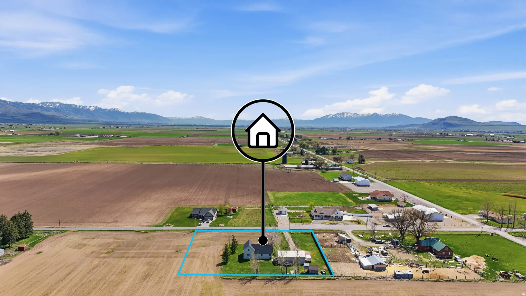 Overview of rural landscape with large plots for crops, property parcel outlined, and a mountain backdrop