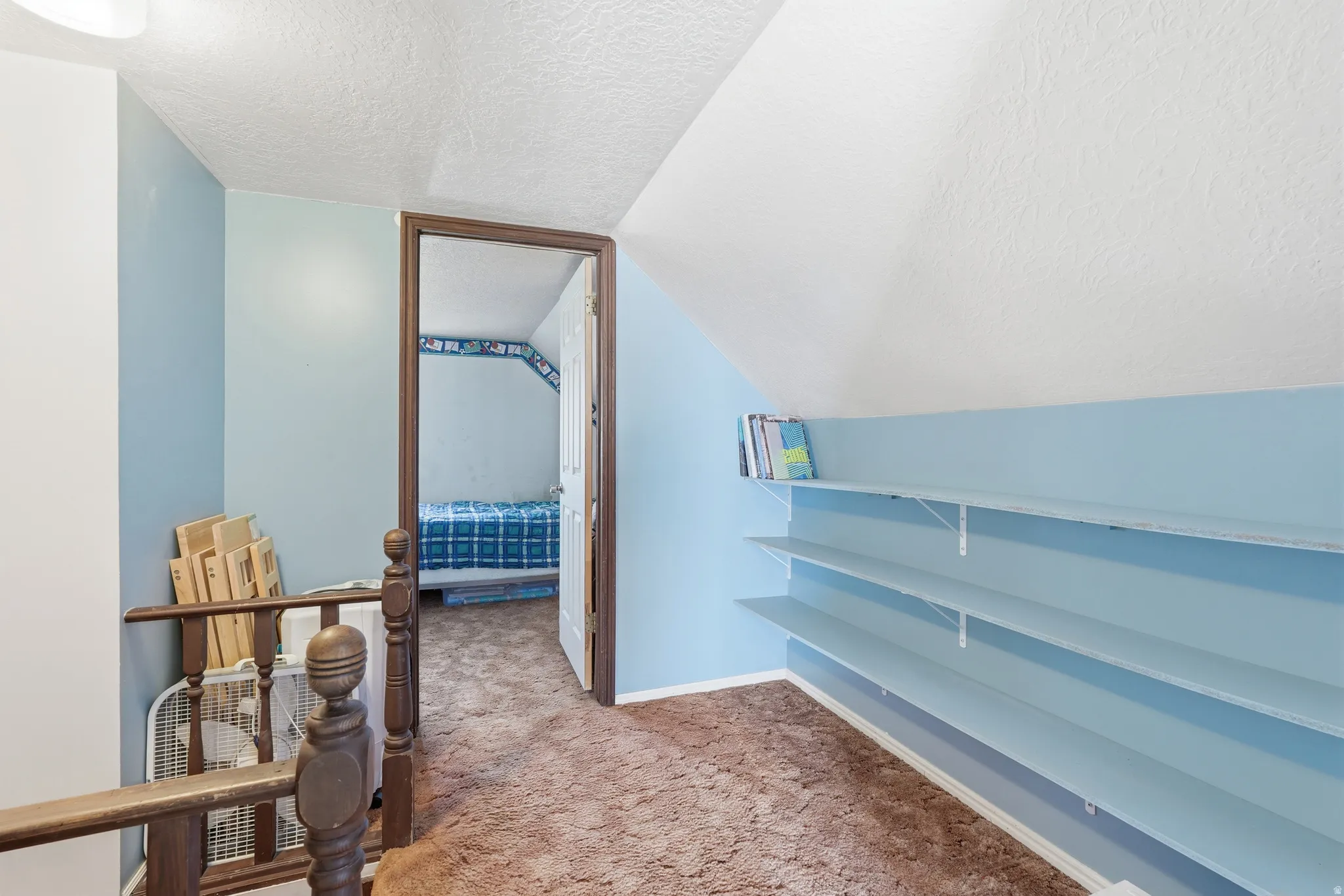 Hall featuring a textured ceiling and light carpet