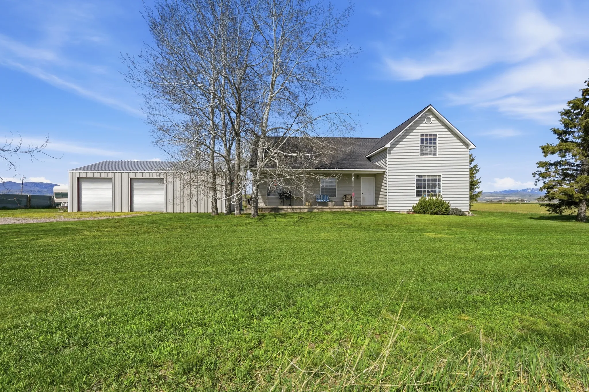 View of front of house with a garage, a front yard, a shingled roof, and driveway