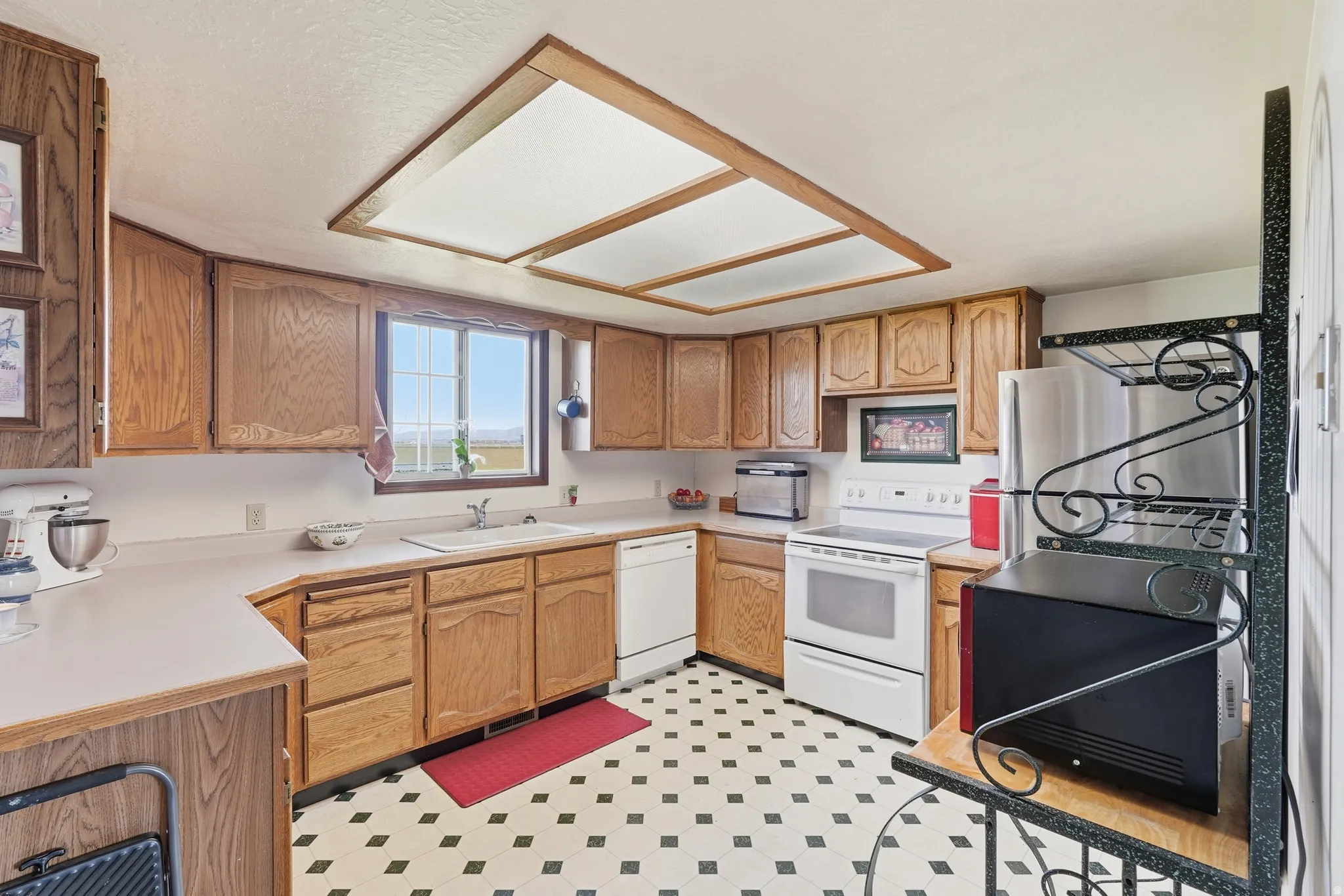Kitchen with light floors, light countertops, white appliances, and wood finish cabinetry