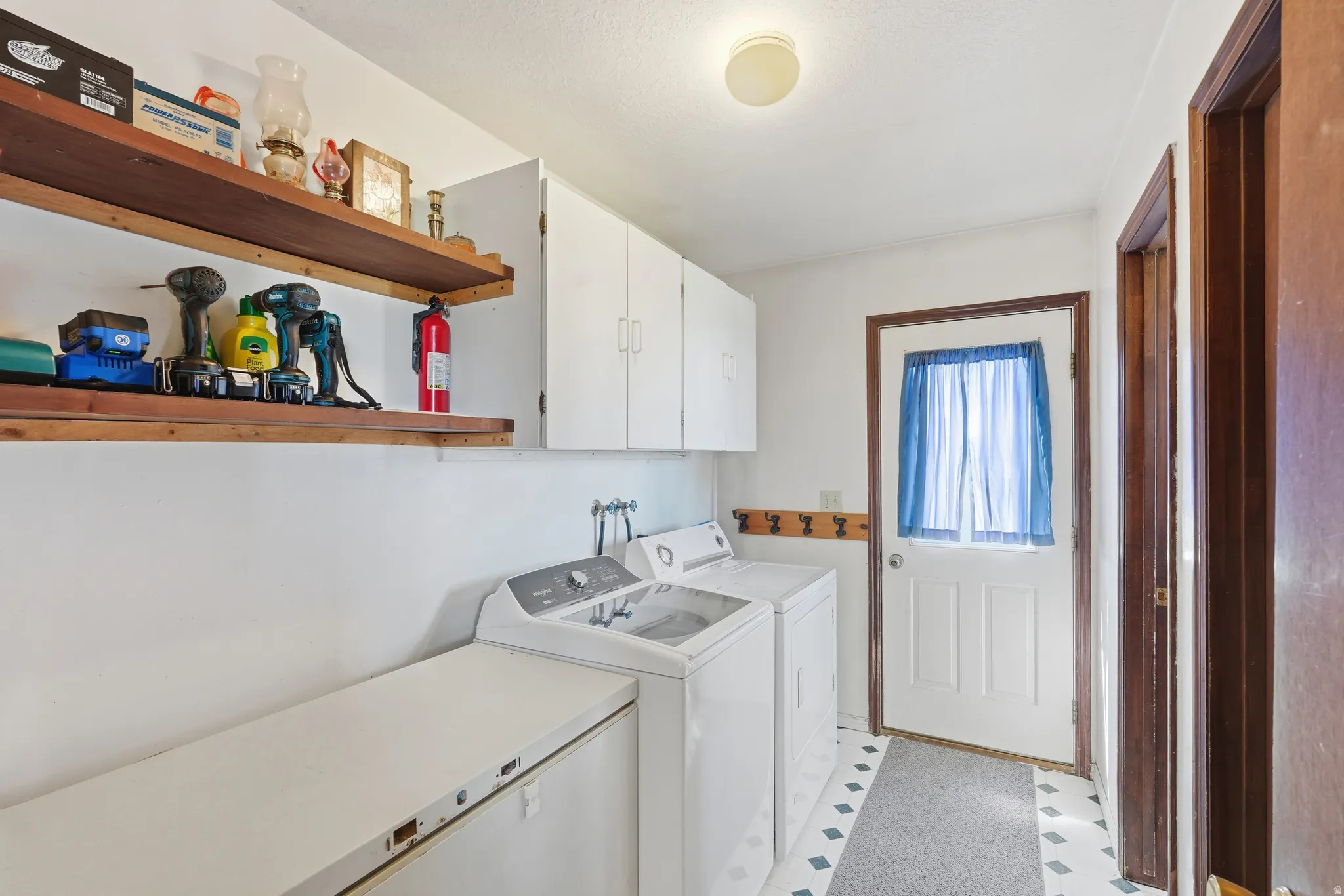Laundry room featuring light floors, cabinet space, and washing machine and clothes dryer