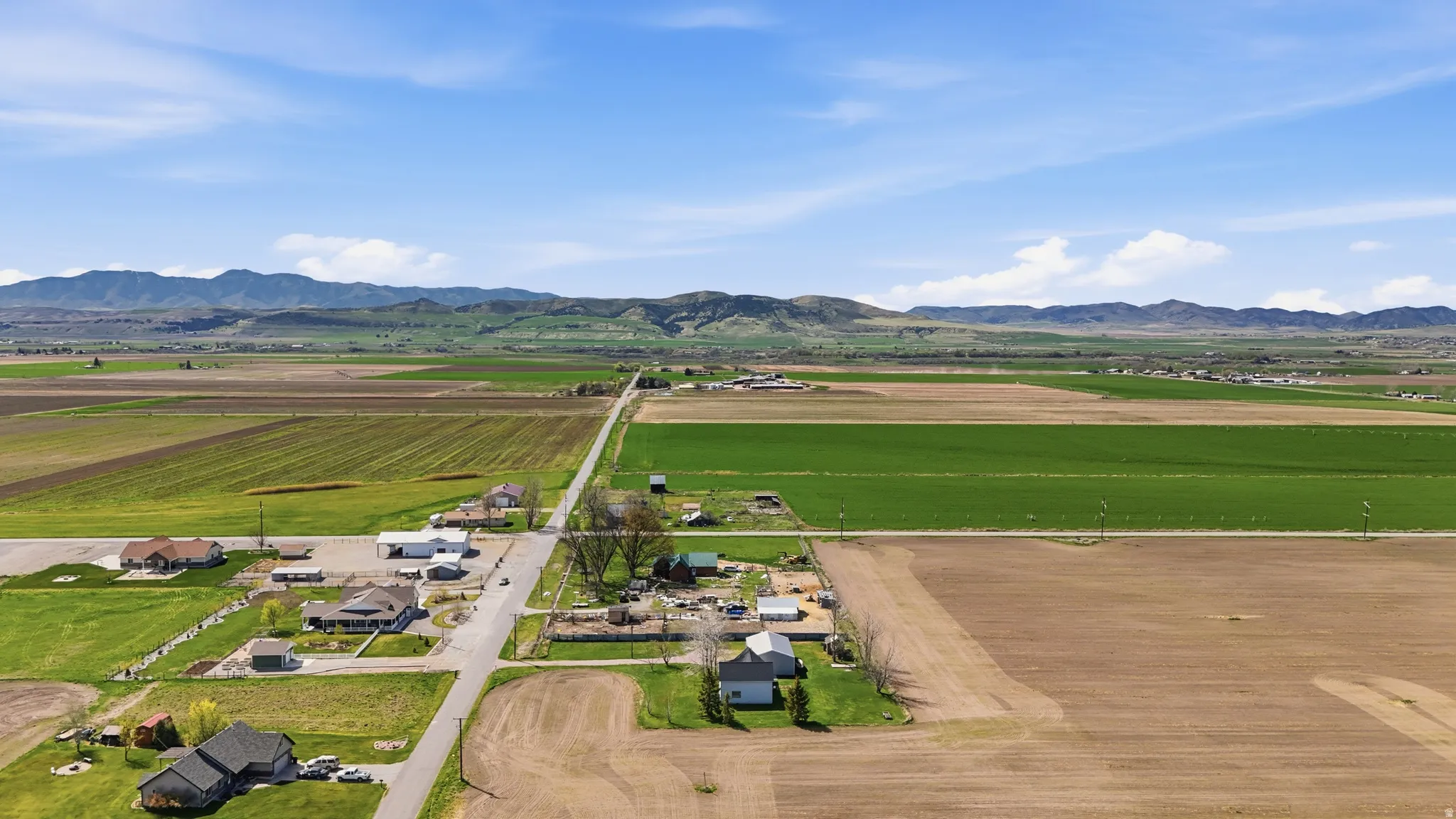 Overview of rural landscape featuring large plots for crops and a mountain backdrop