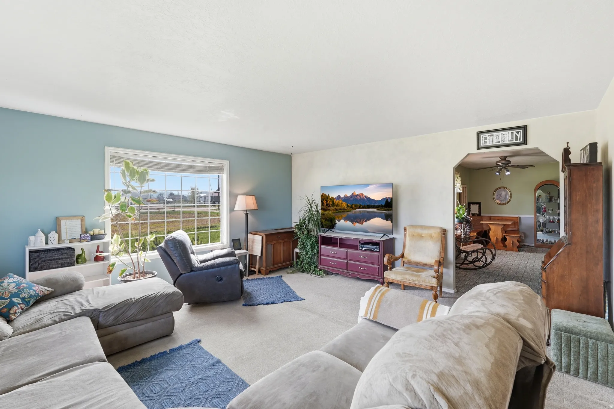 Carpeted living area featuring ceiling fan and arched walkways
