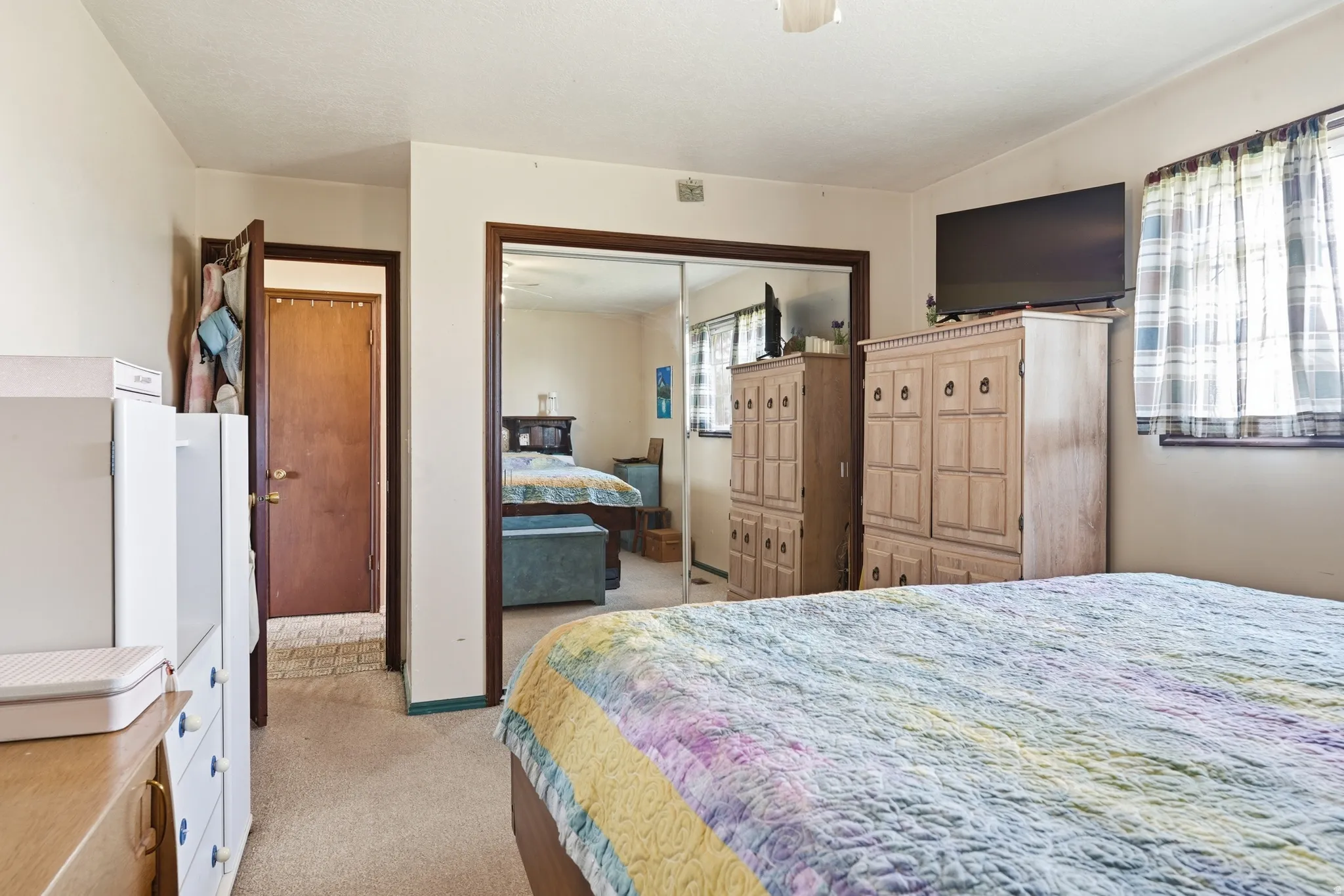 Bedroom with light colored carpet, ceiling fan, and a closet