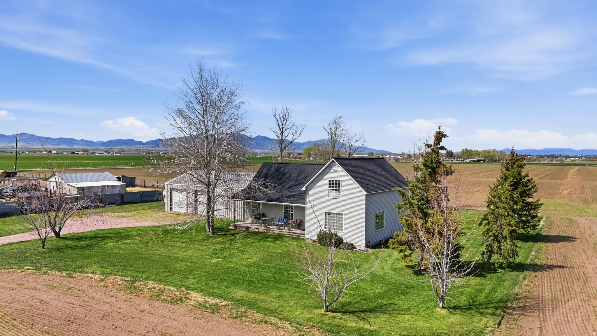 View of front of home featuring dirt driveway, a mountain view, a shingled roof, a view of rural / pastoral area, and a garage