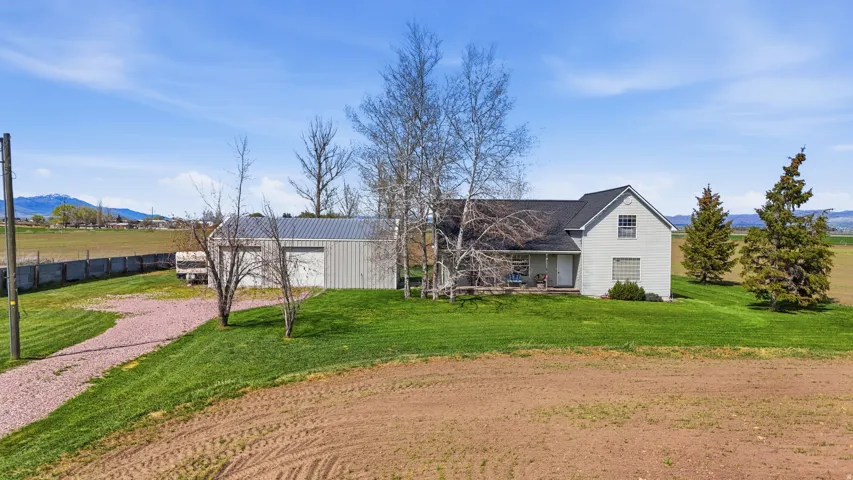 View of front of property featuring a mountain view, driveway, a front yard, a garage, and a view of rural / pastoral area