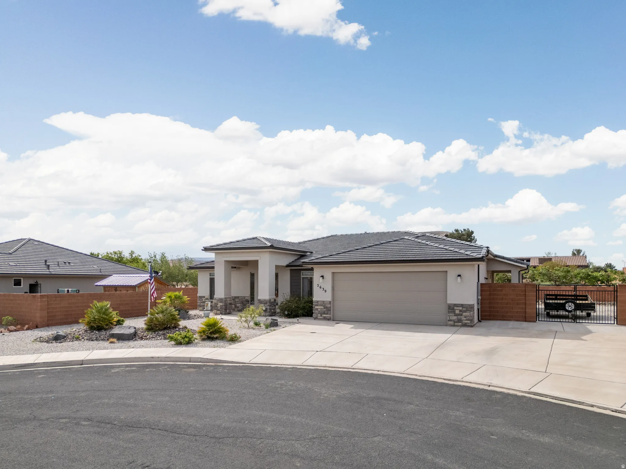 Prairie-style home with stucco siding, an attached garage, driveway, and a gate