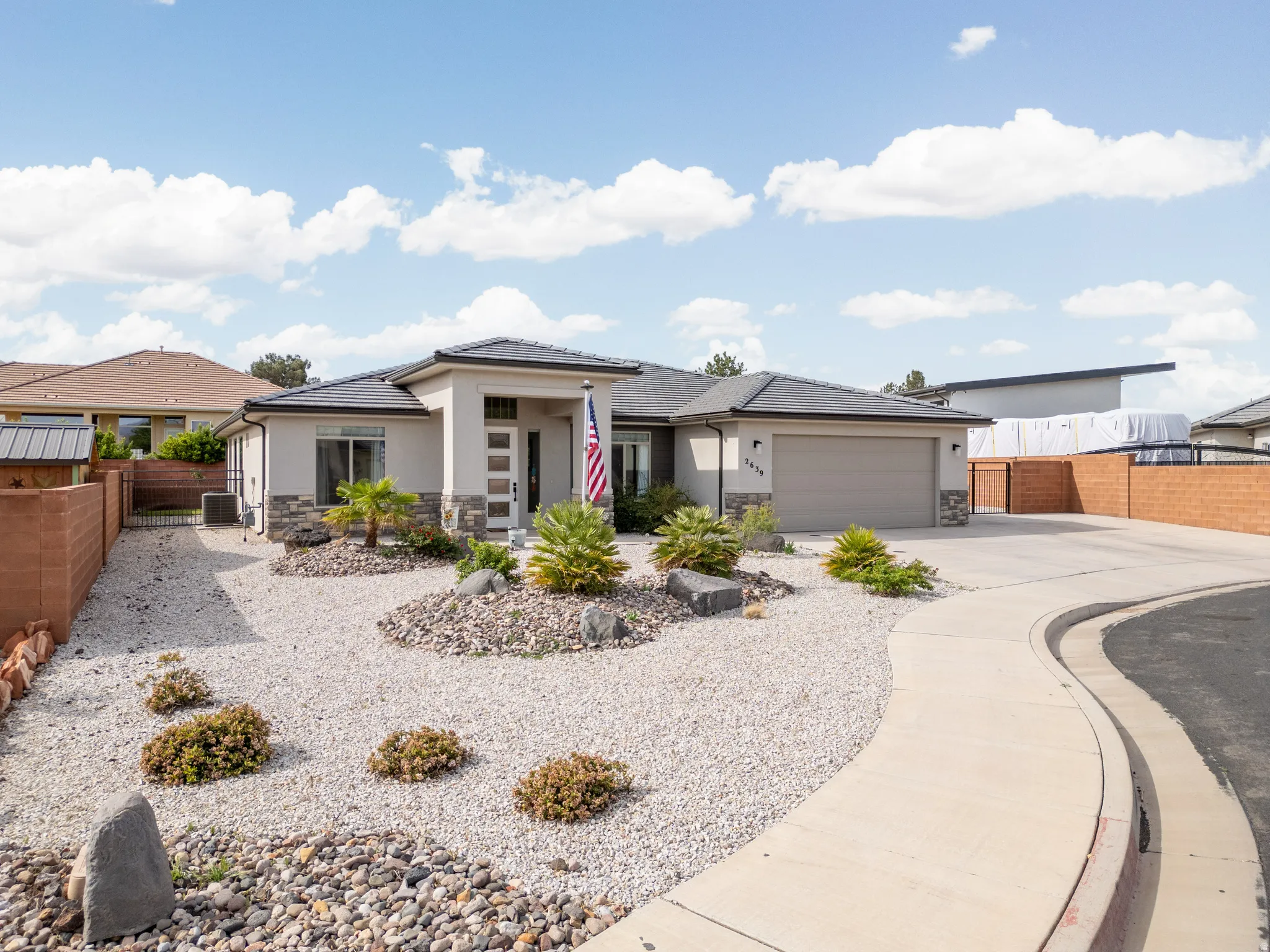 Prairie-style house featuring stone siding, driveway, stucco siding, a garage, and a tiled roof