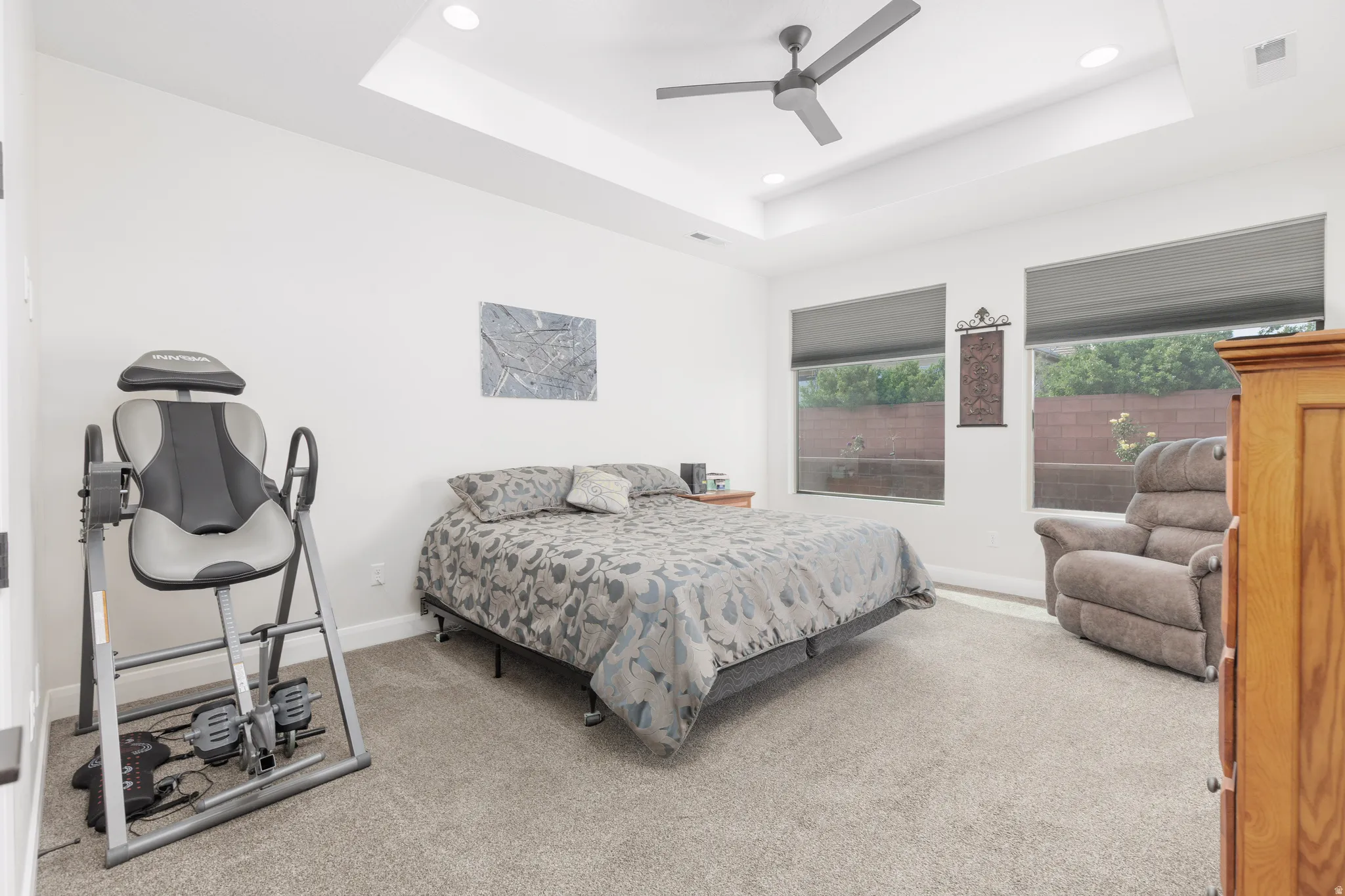 Carpeted bedroom with ceiling fan, recessed lighting, and a raised ceiling