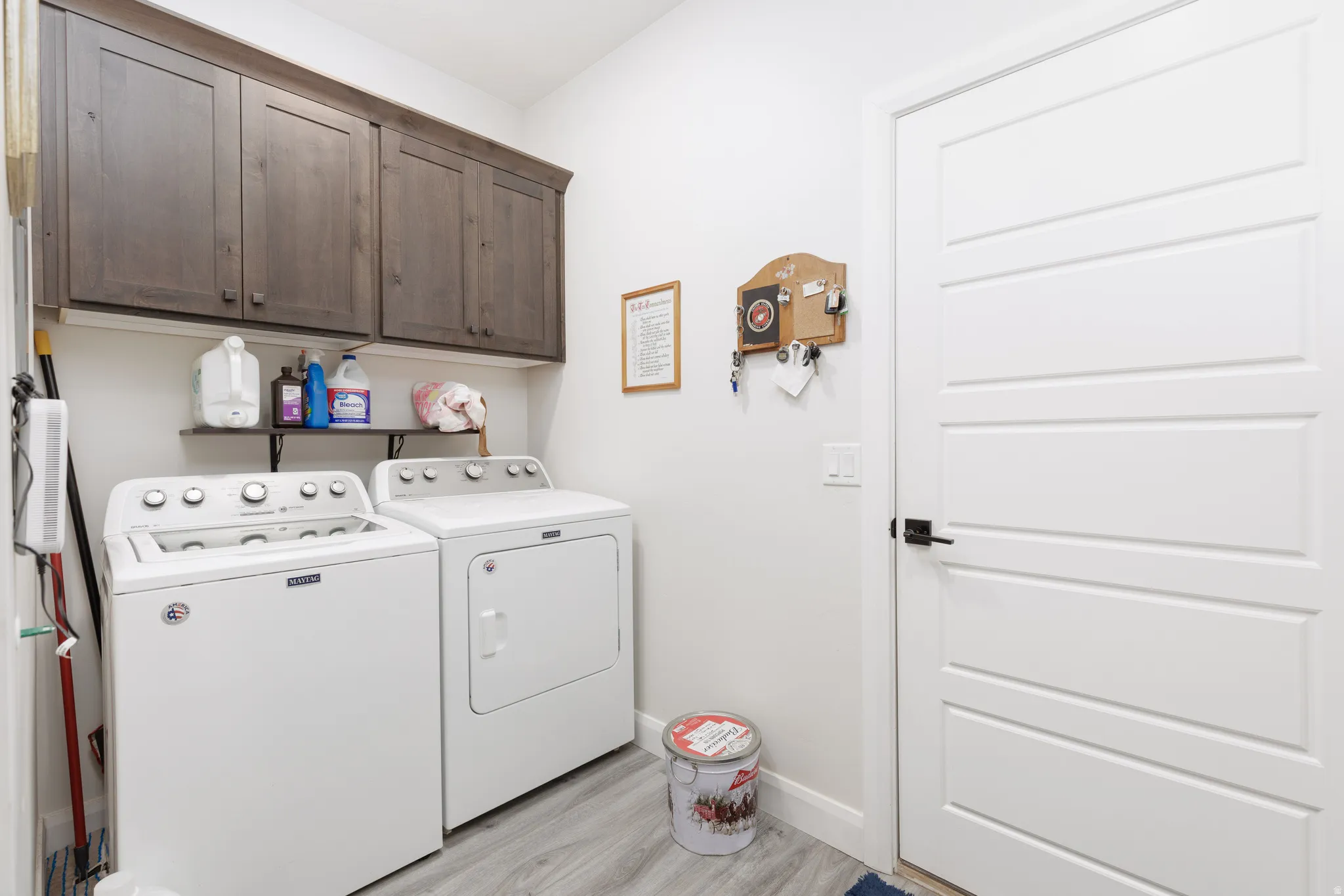 Laundry room featuring independent washer and dryer, light wood-type flooring, and cabinet space