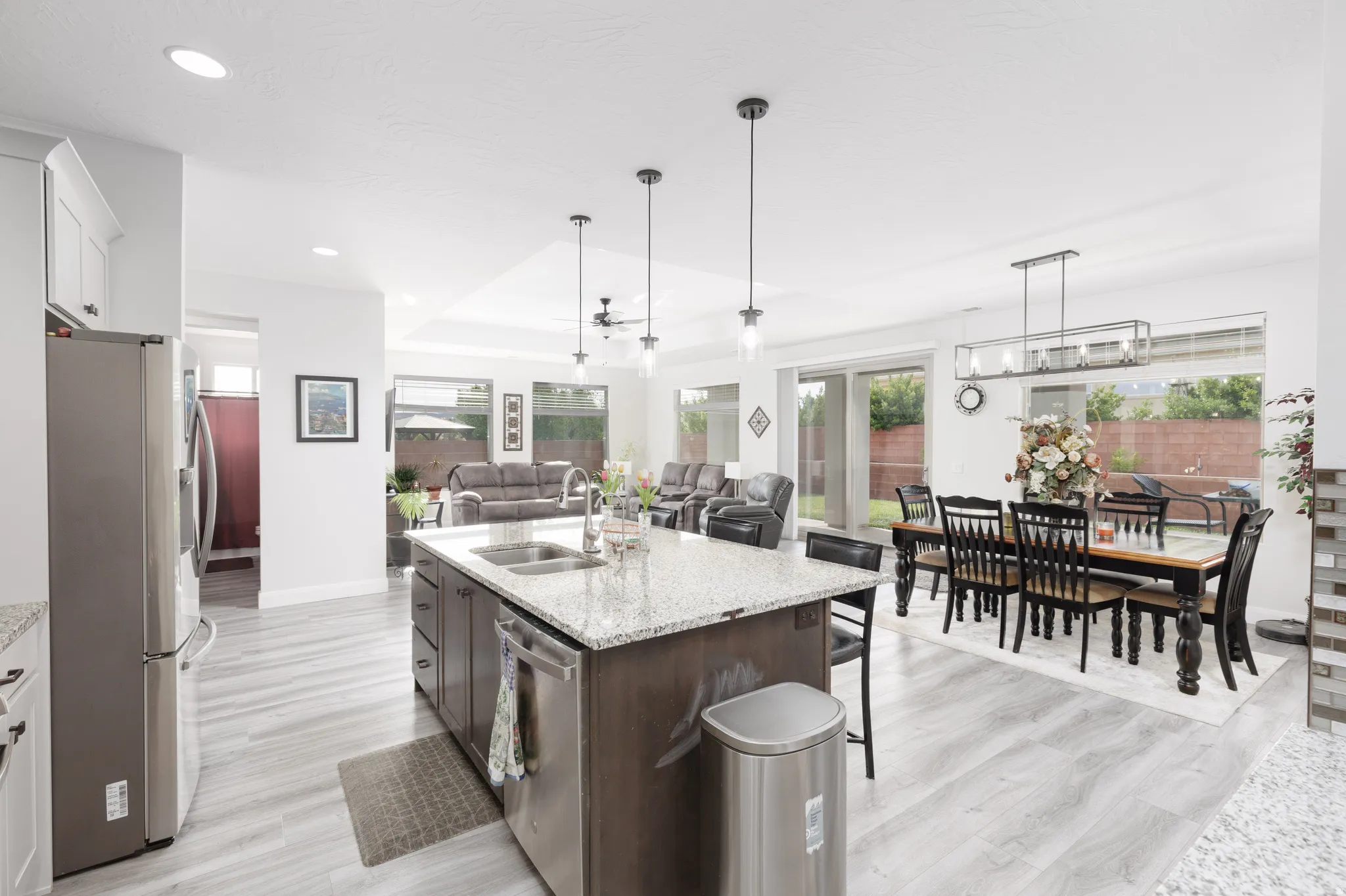 Kitchen with light stone countertops, open floor plan, stainless steel appliances, a kitchen bar, and dual tone cabinets