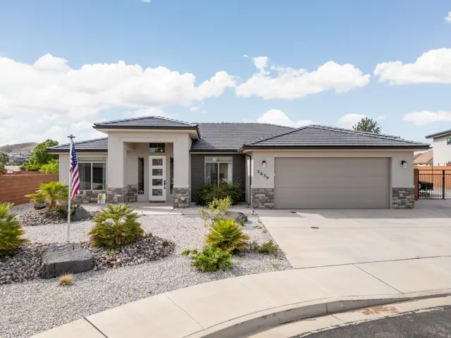 Prairie-style house with stone siding, driveway, a garage, a tiled roof, and stucco siding