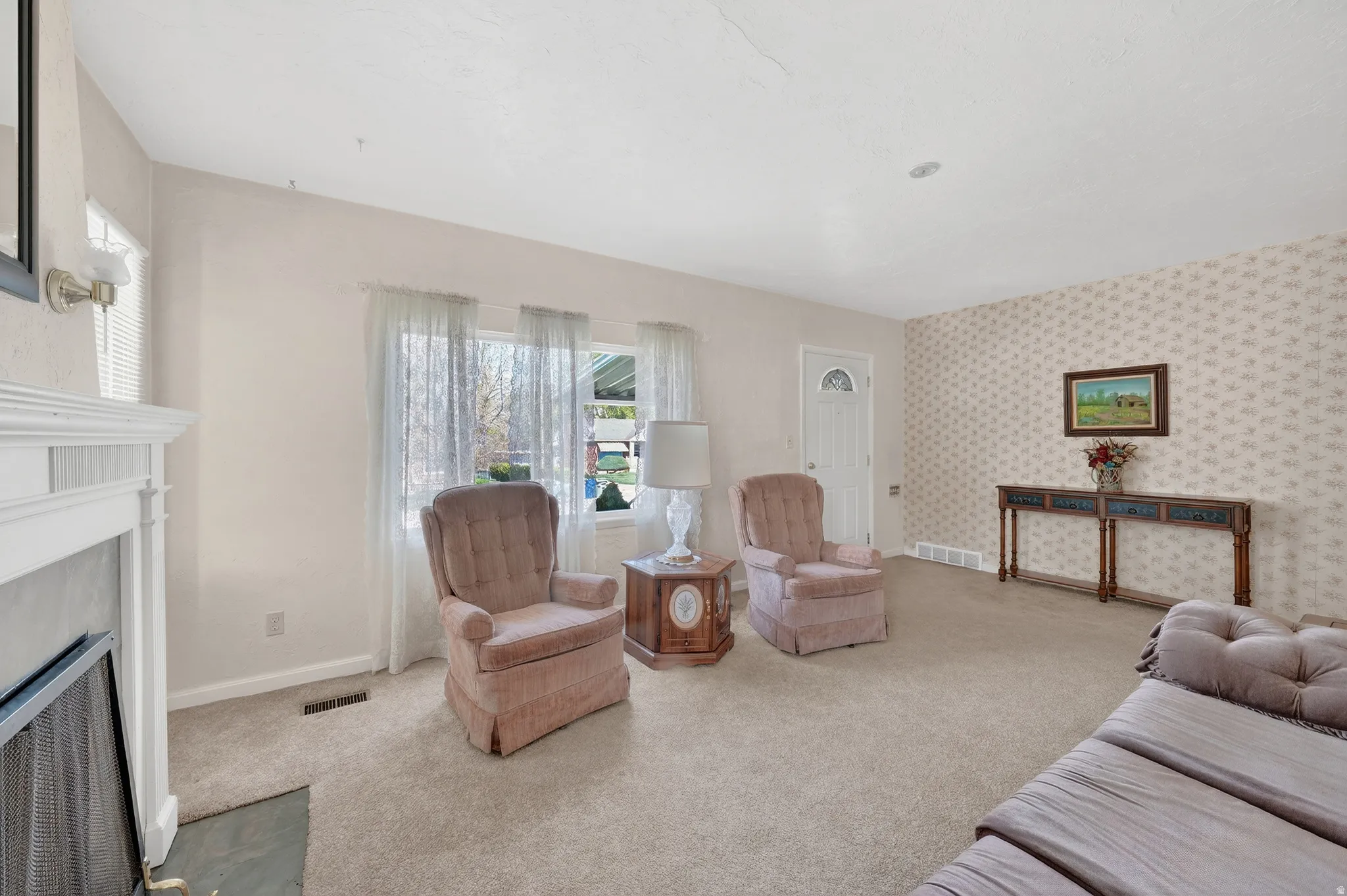 Carpeted living area with a fireplace with flush hearth and wallpapered walls