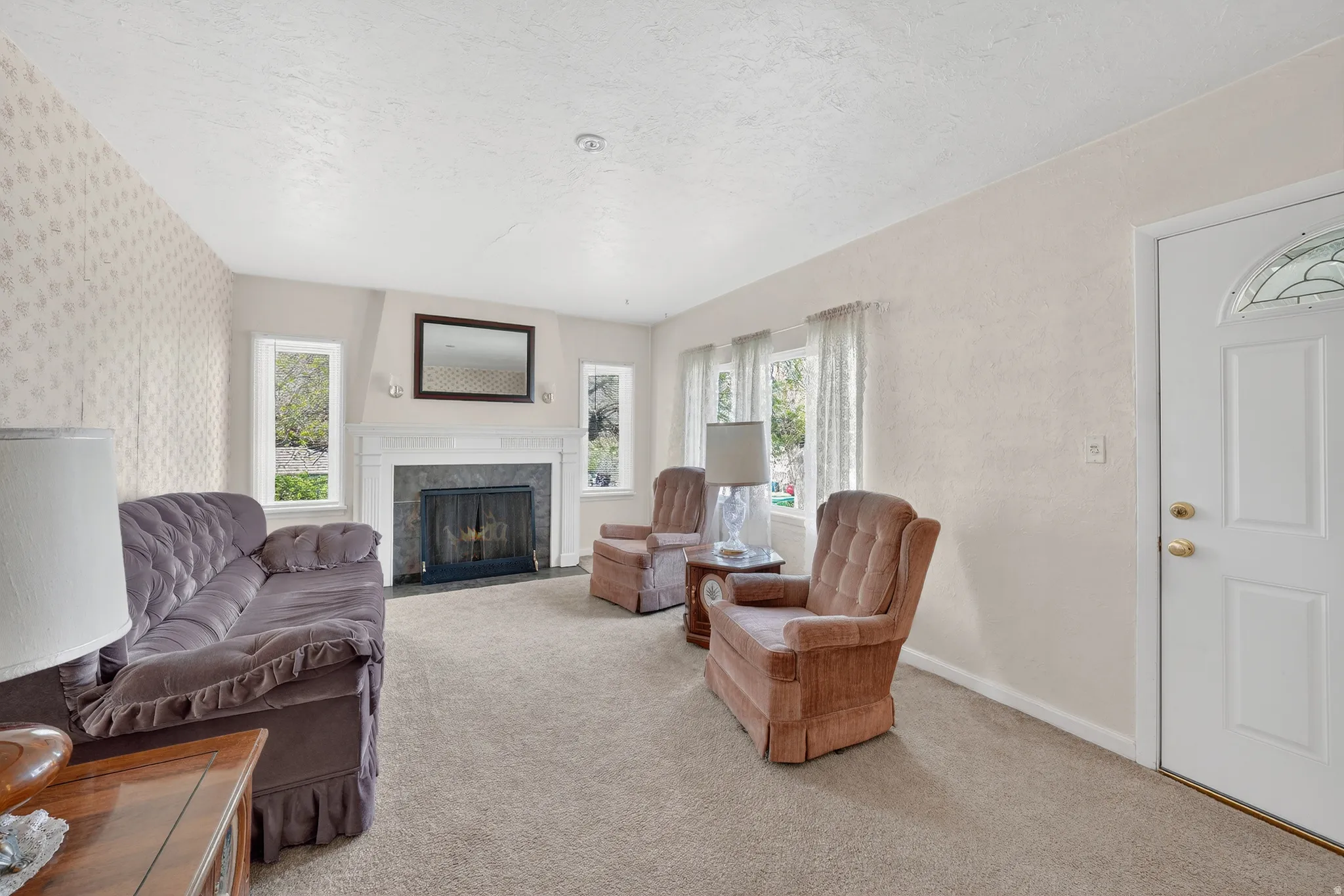 Carpeted living room with a textured ceiling and a premium fireplace