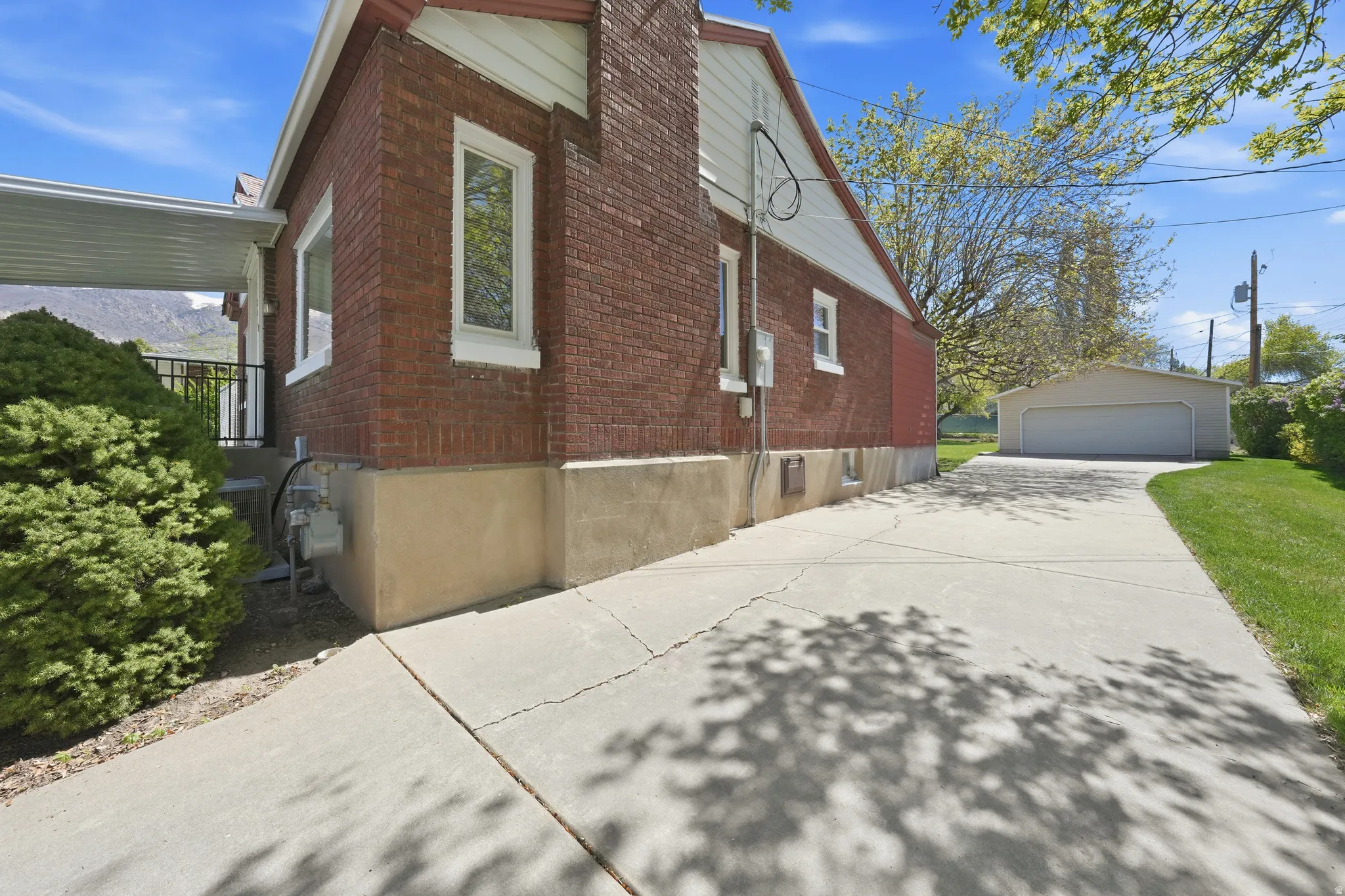 View of home's exterior featuring a garage, brick siding, and an outbuilding