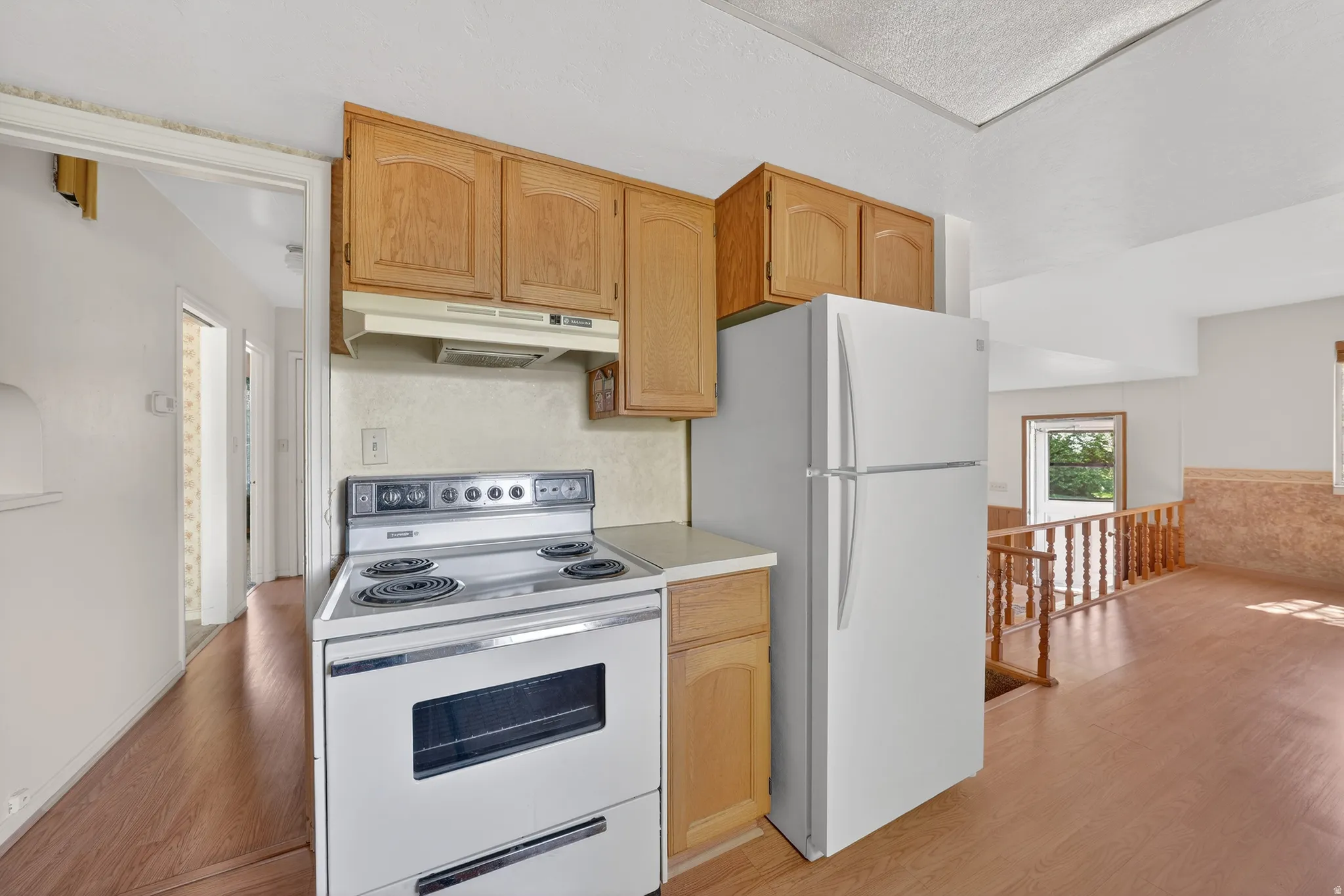 Kitchen featuring white appliances, light countertops, light wood-style floors, and light wood finish cabinetry