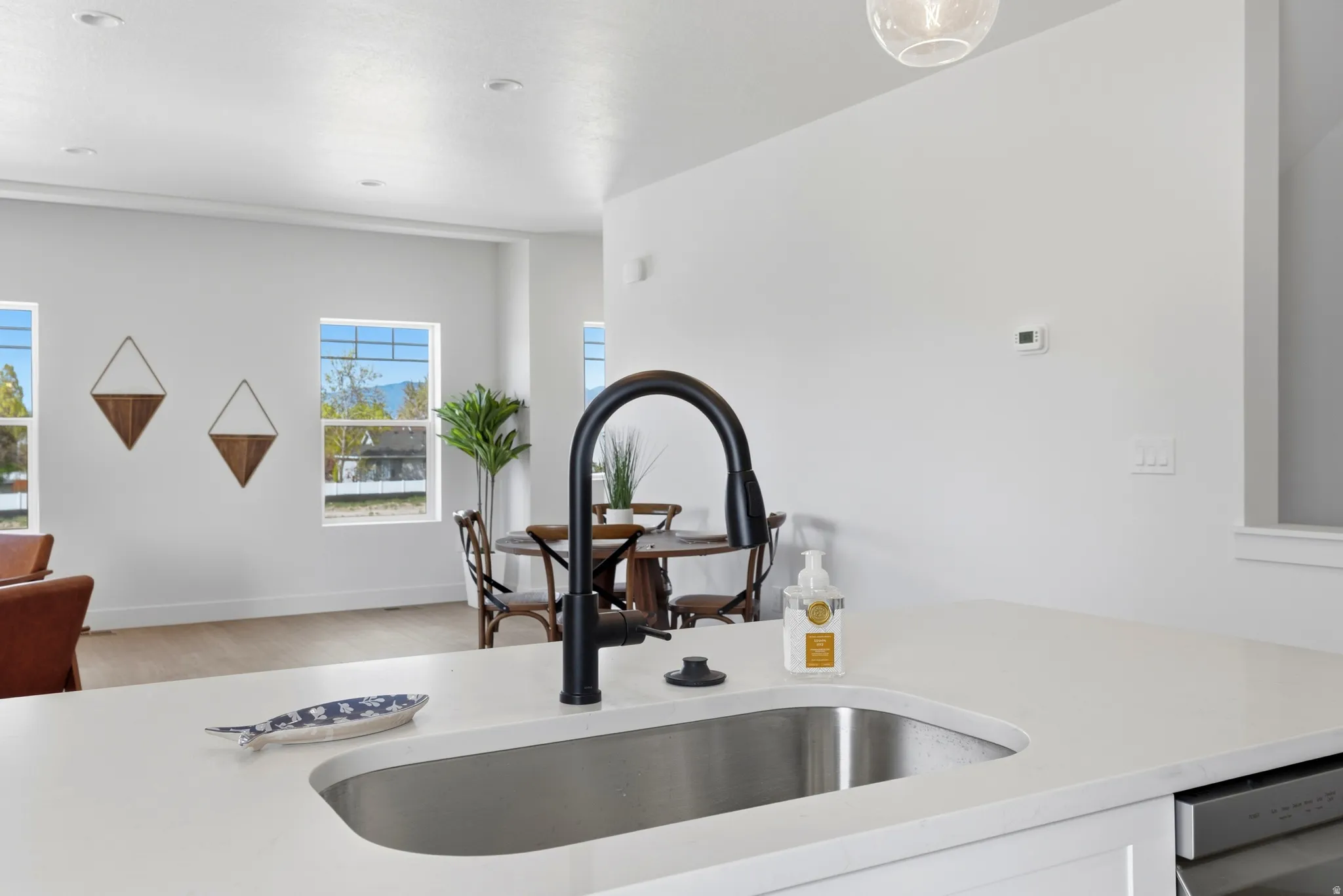 Kitchen view of light stone countertops, dishwasher, and light wood finished floors