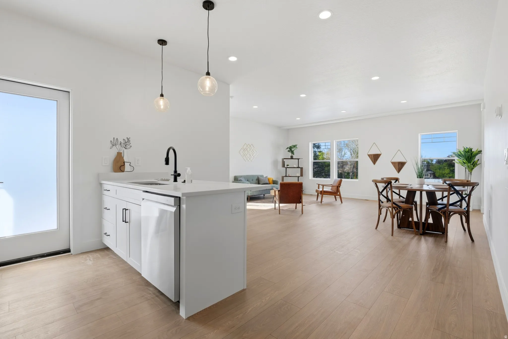 Kitchen with white cabinetry, a peninsula, light wood-style flooring, and hanging light fixtures