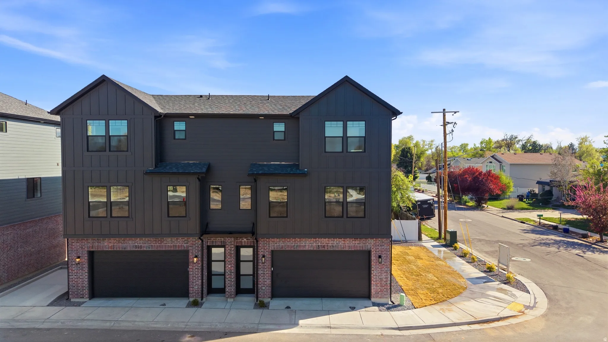 View of front facade with board and batten siding, an attached garage, and brick siding