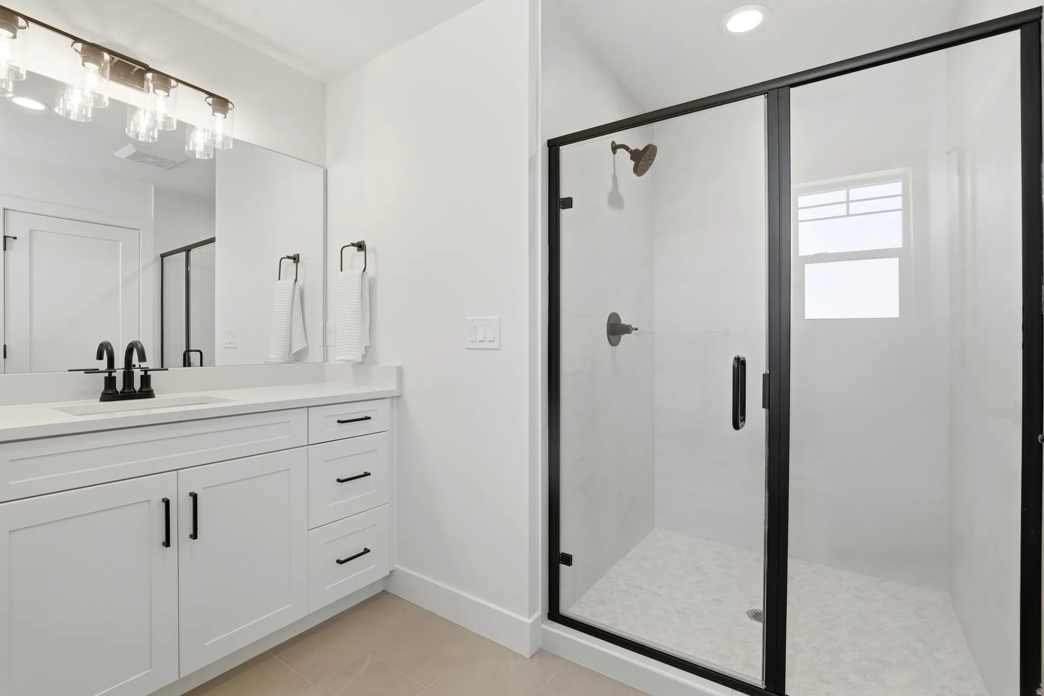Full bath featuring vanity, a shower stall, and light tile patterned floors