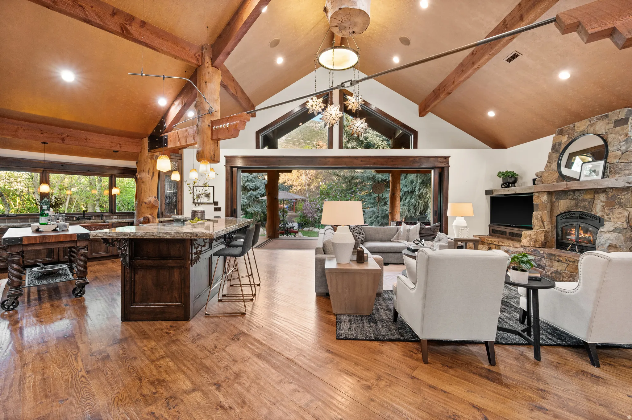 Living area featuring light wood finished floors, a stone fireplace, and suspended lighting