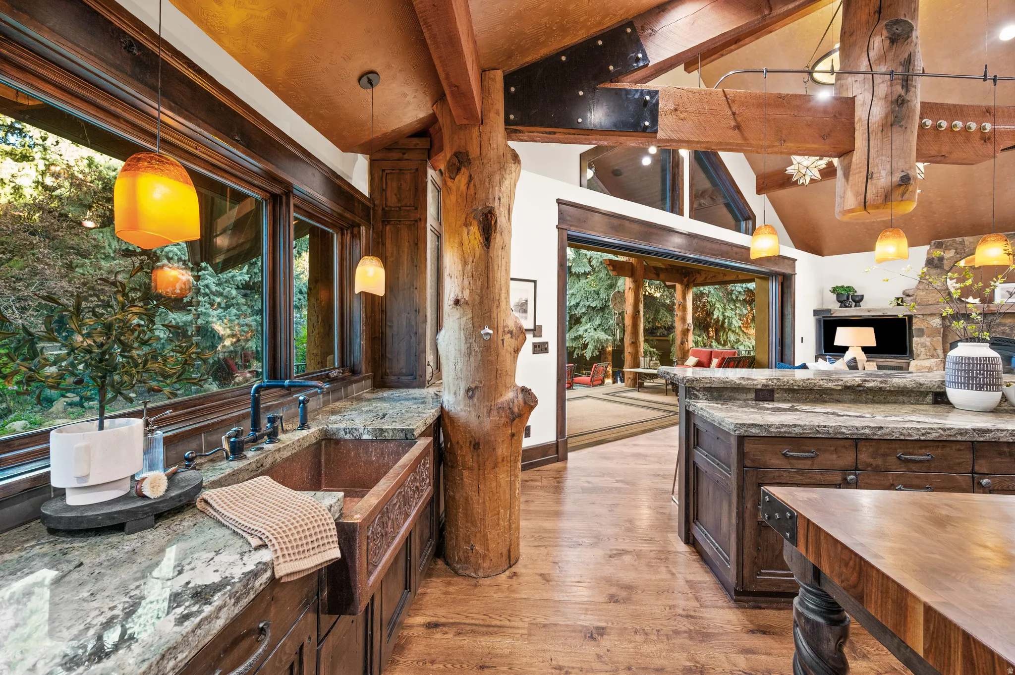 Kitchen with pendant lighting, dark wood finish cabinetry, light wood-style floors, vaulted ceiling, and dark stone countertops