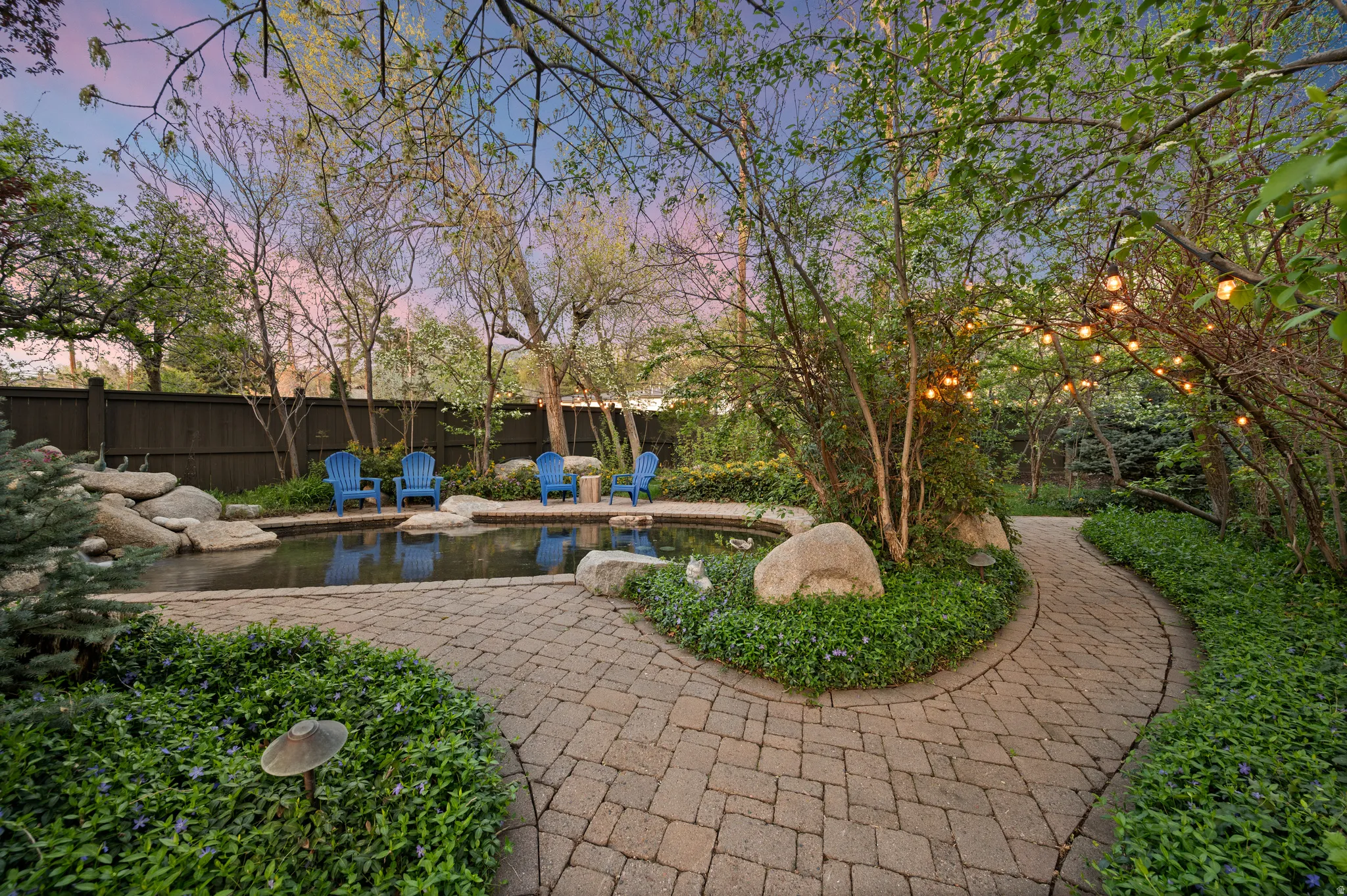 View of property's walkway and pond located inside fenced backyard