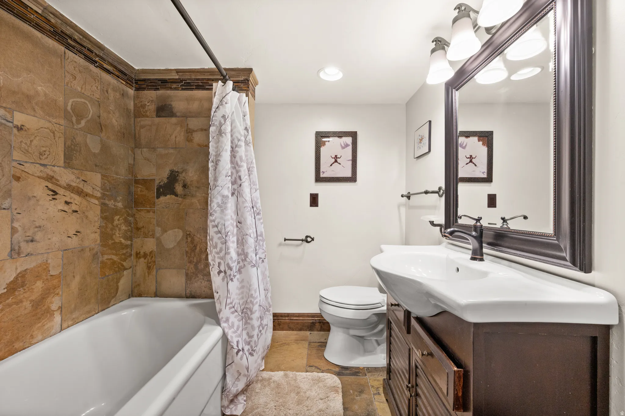 Full bath with vanity, shower / tub combo, stone tile floors, and recessed lighting