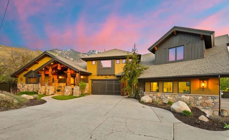 Craftsman-style home with stone siding, roof with shingles, driveway, and a garage