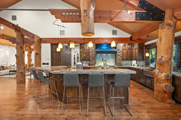 Kitchen featuring light stone countertops, dark wood finish cabinetry, tasteful backsplash, lofted ceiling, and dark wood finished floors