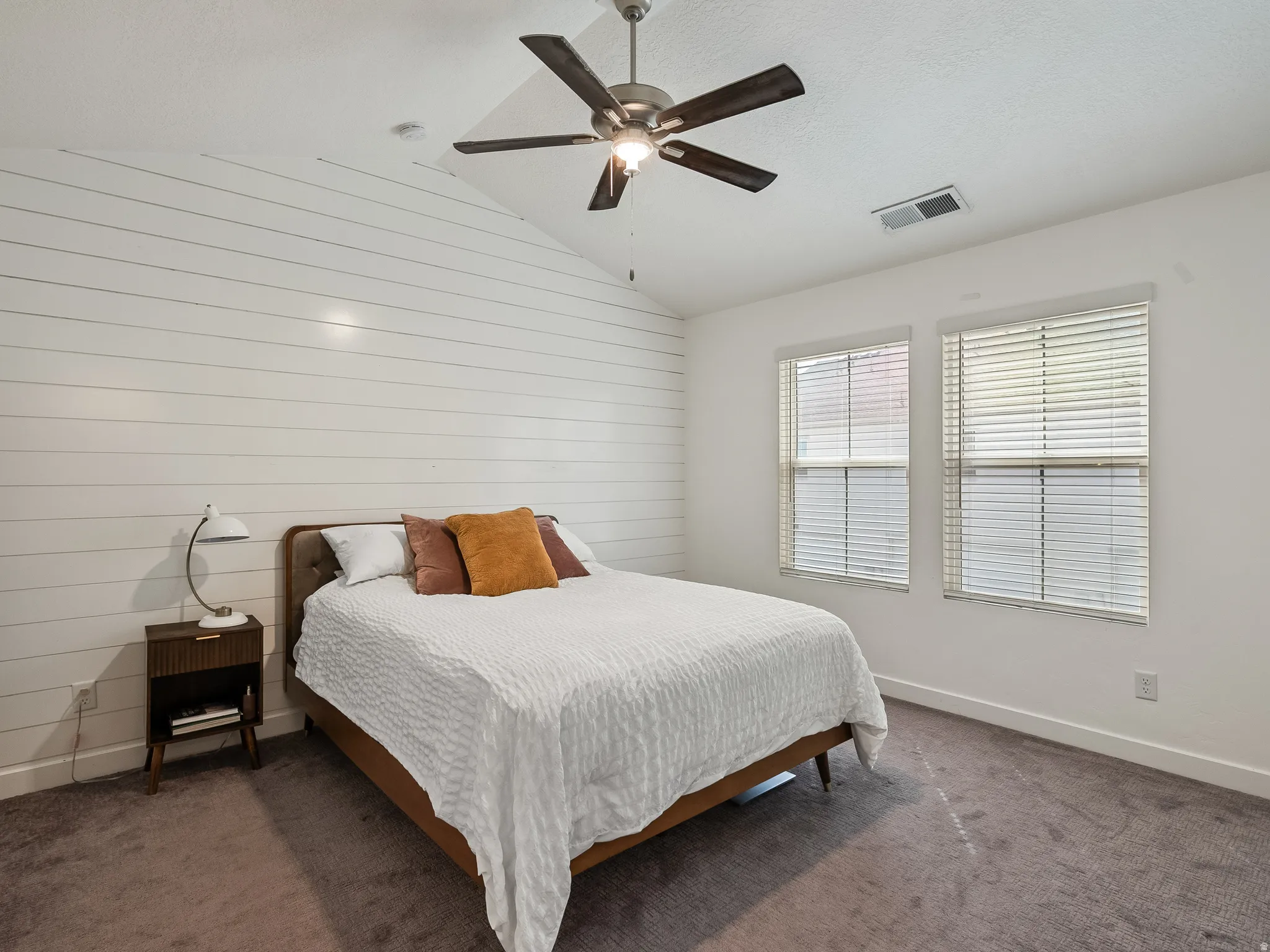Bedroom featuring carpet, wood walls, and a ceiling fan
