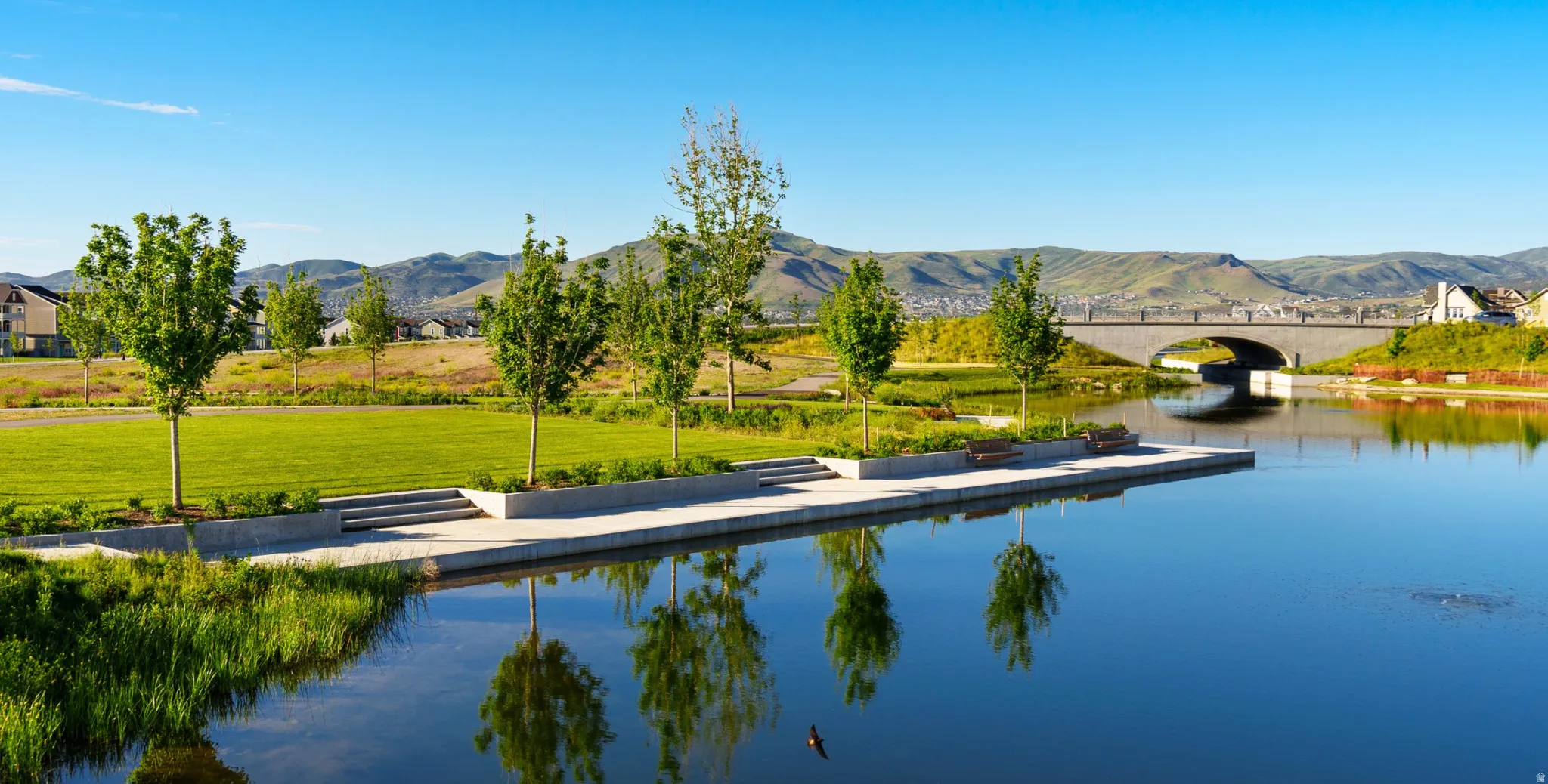 Water view with a floating dock, a mountain backdrop, and a notable bridge