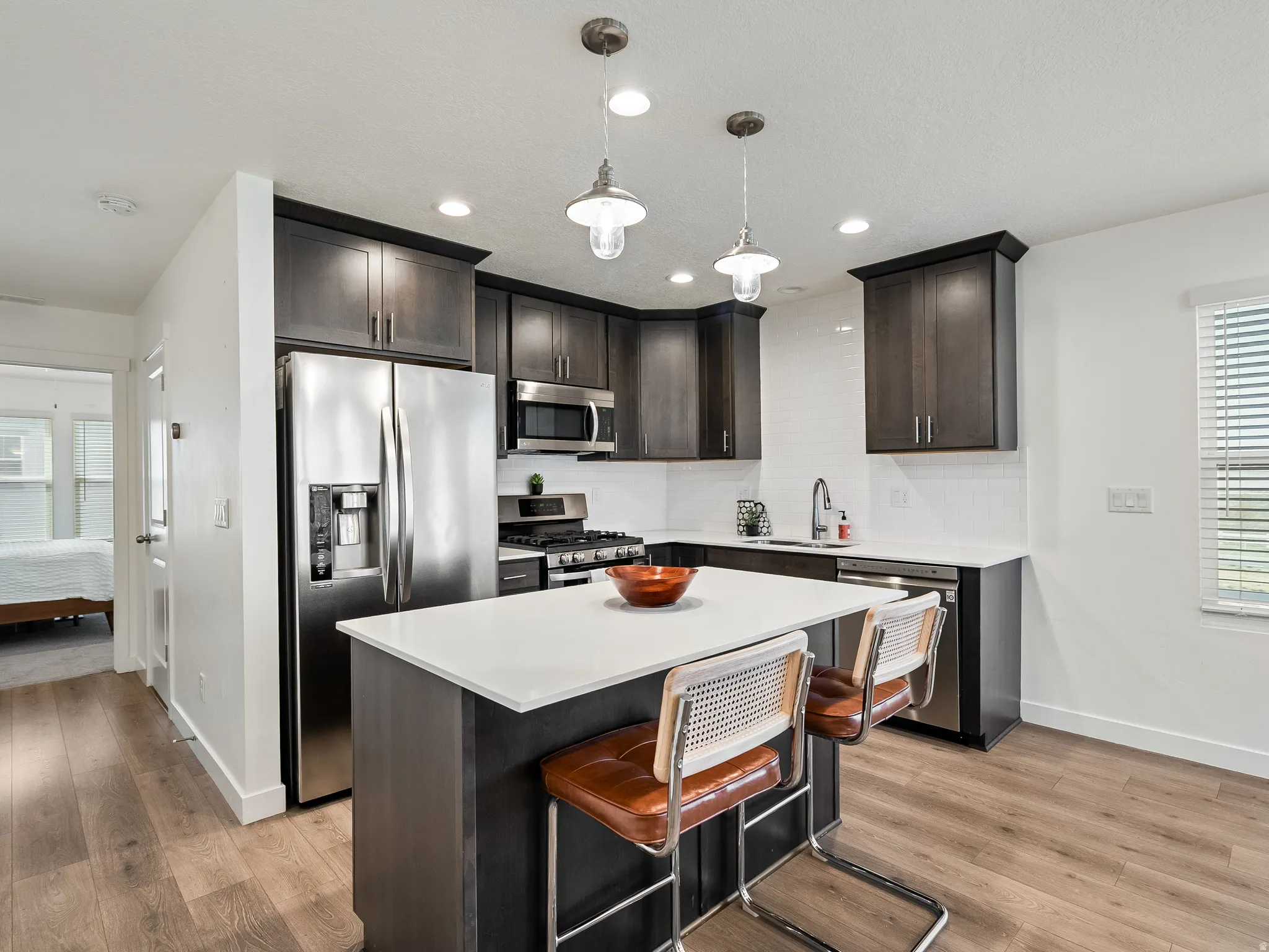 Kitchen featuring healthy amount of natural light, dark wood finish cabinets, stainless steel appliances, and a center island